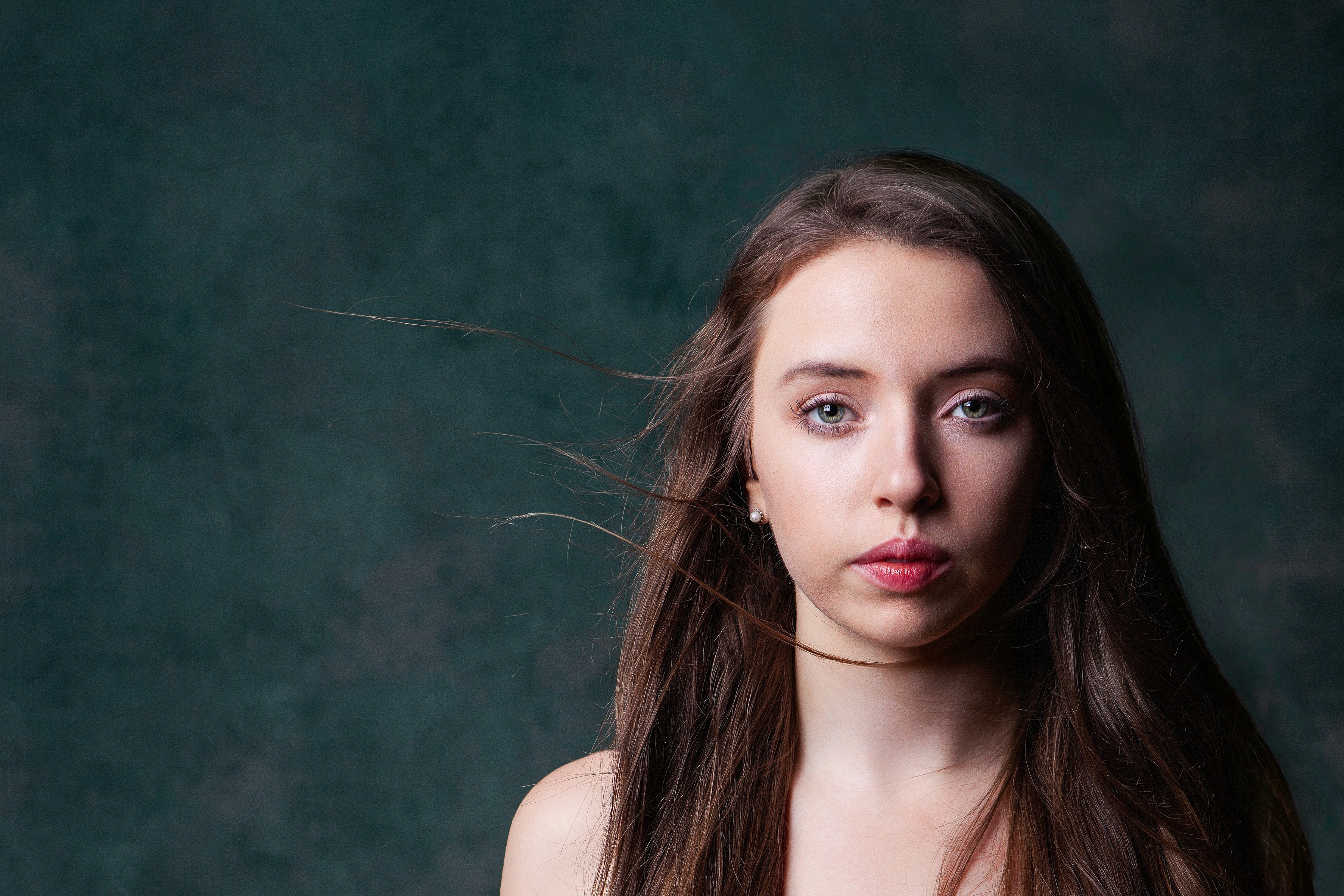 Editorial portrait of a woman against a dark textured background, conveying confidence, presence, and modern personal branding.