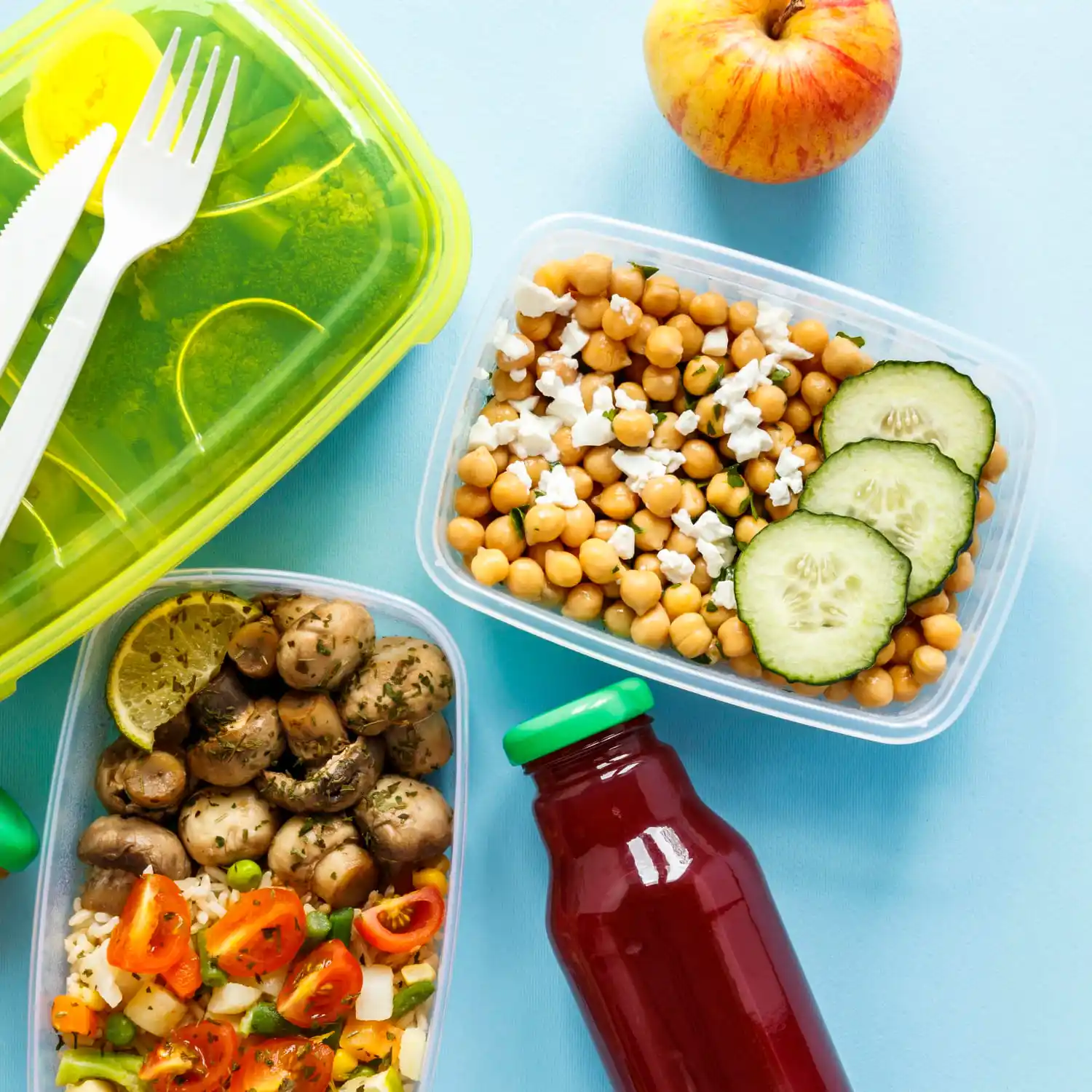 Healthy meal prep in containers with juice and an apple.