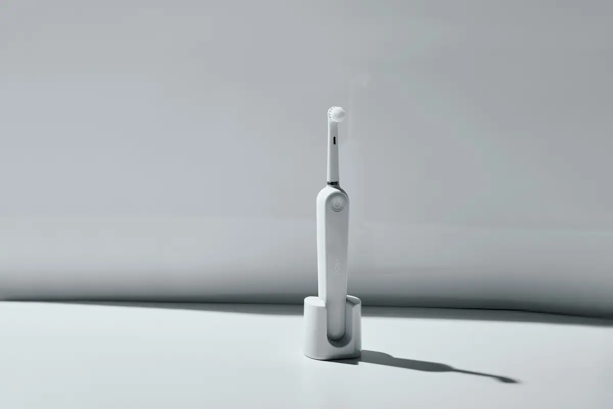 Minimalist electric toothbrush standing on a clean surface with soft natural light.