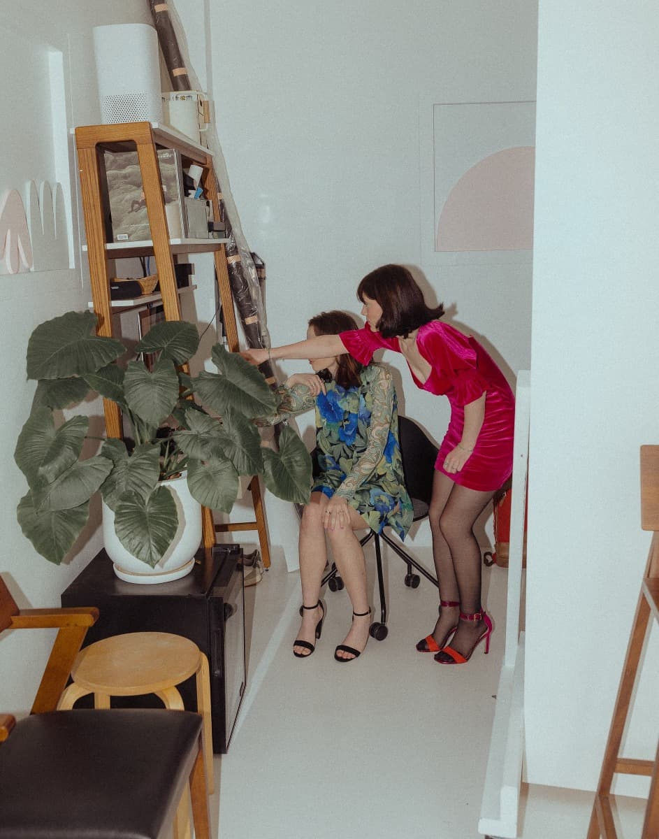 Behind-the-scenes moment of two models reviewing images during a creative photoshoot at Revelator Studio, Shreveport’s leading natural light studio.