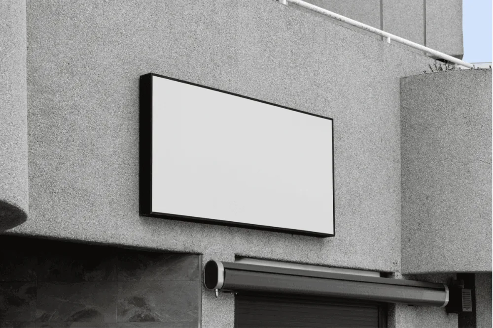 Outdoor wall-mounted black sign mockup with red geometric accents. Placed against a textured gray concrete wall, perfect for showcasing branding or logo designs.