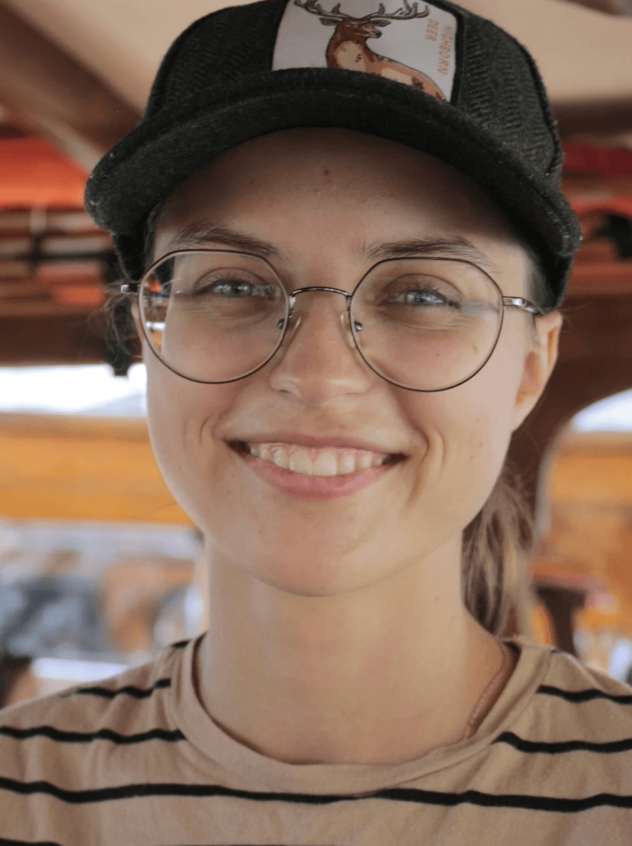 A woman wearing glasses and a hat smiling