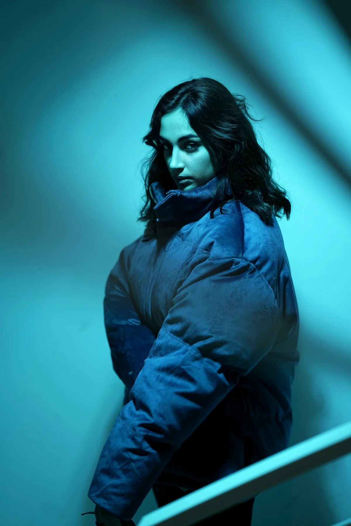 Model in a blue jacket under cyan light