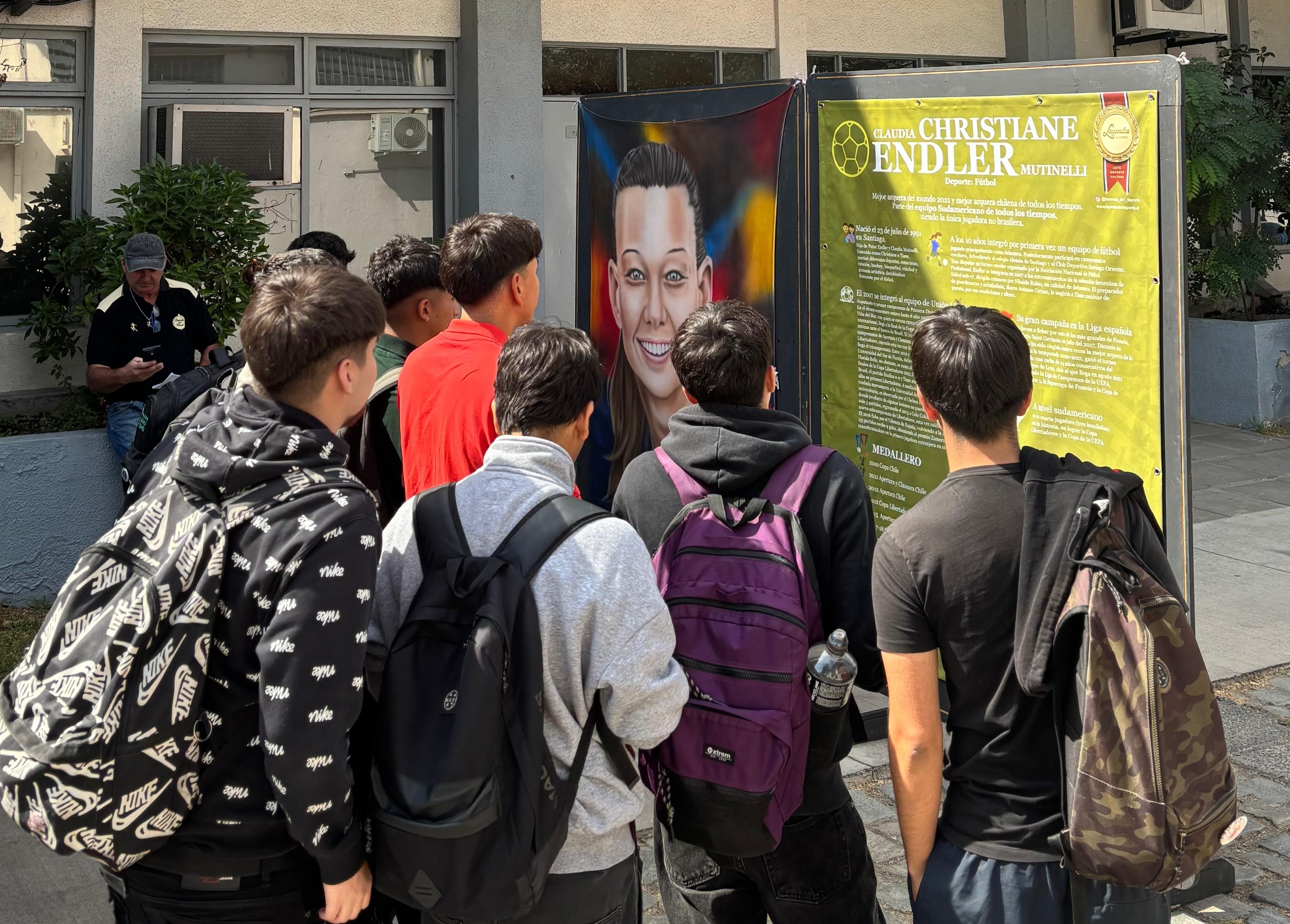 Visitantes en la exposición Leyendas del Deporte admirando la pintura de Christiane Endler, arquera de fútbol chilena.