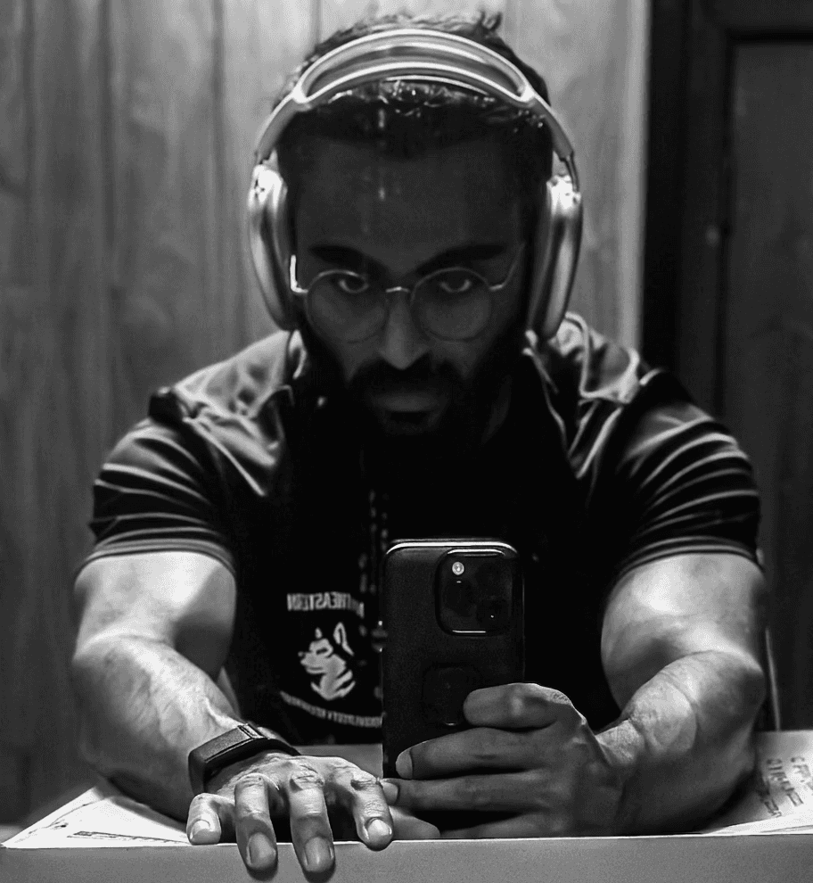 A close-up of a person wearing green-tinted glasses, with a serious expression and smooth skin.