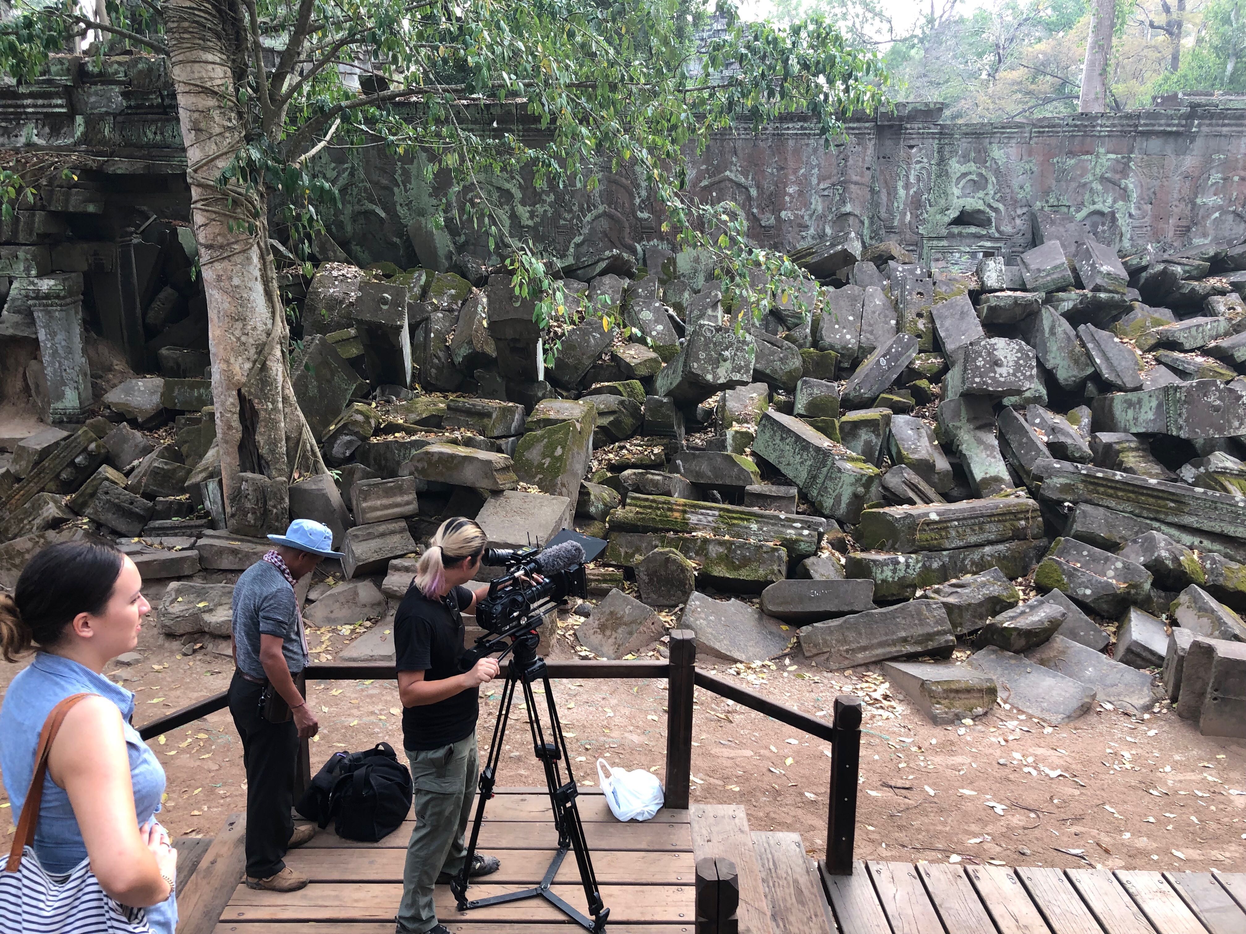 man in black polo shirt wearing white mask holding black camera