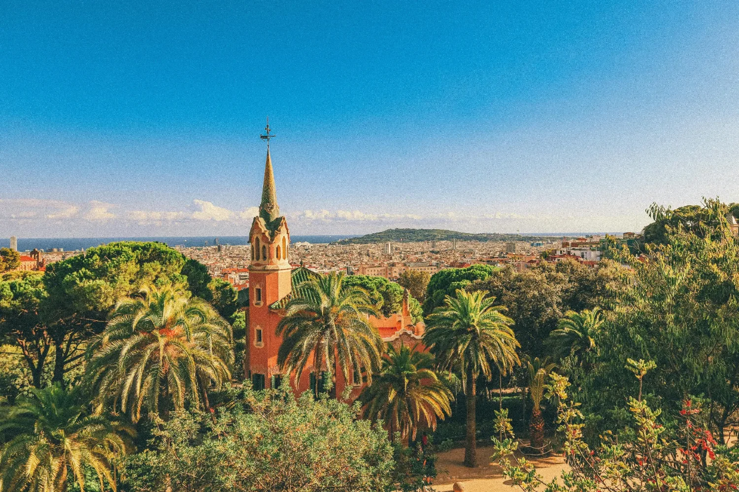 Colorful tower and palm trees in Park Güell, Barcelona, Spain, overlooking the city and sea.