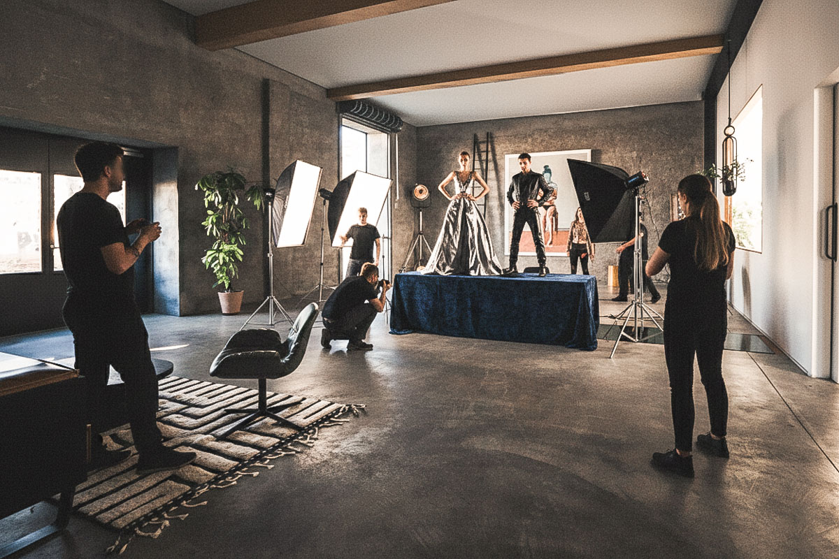 A woman in an orange sweater smiling while looking at a tablet, with a pen in hand.