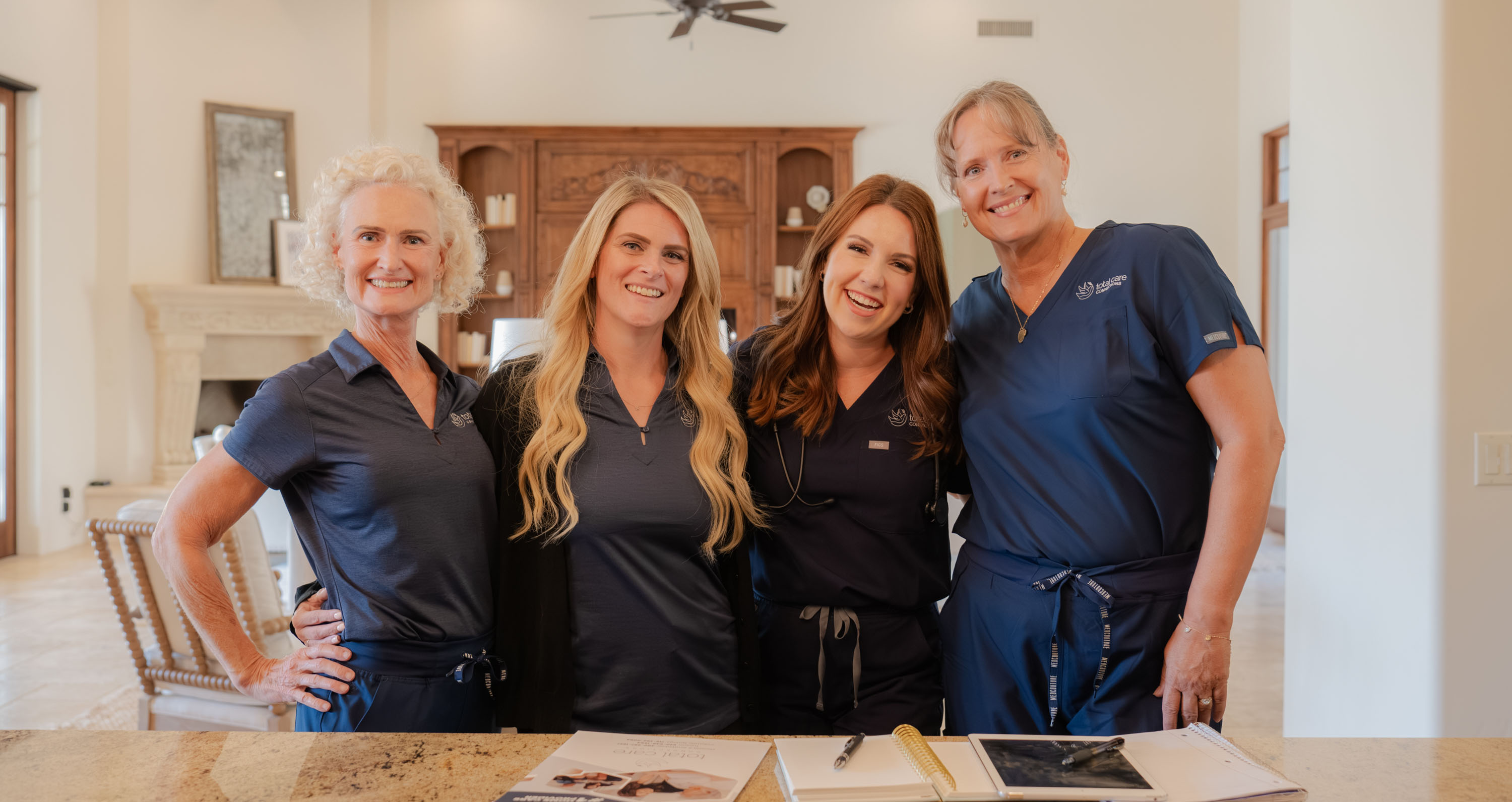 Four women in dark blue medical scrubs standing together behind a counter.