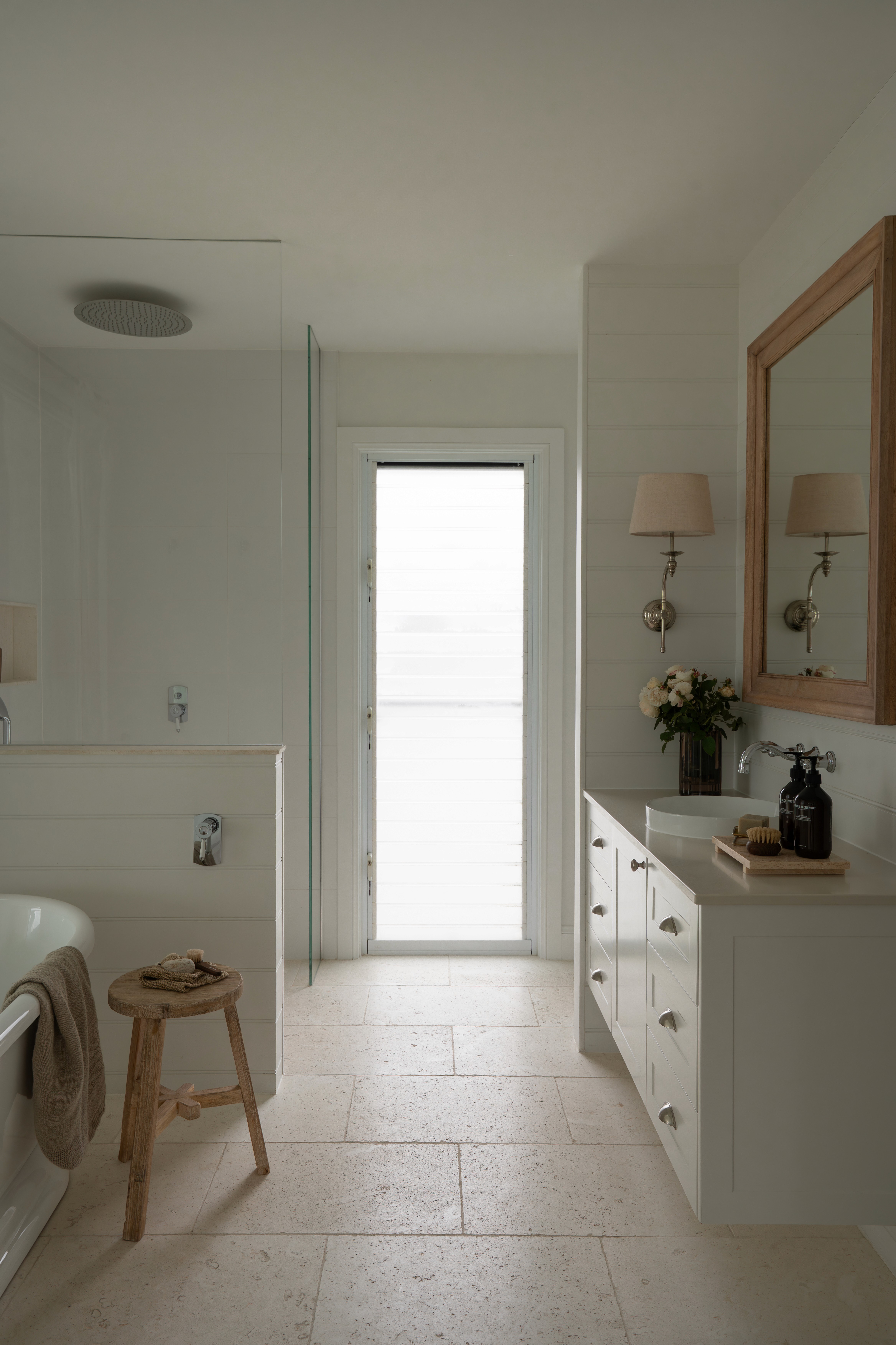 Minimal bathroom interior with neutral finishes, timber-framed mirror and soft natural light at Talm Beach House.