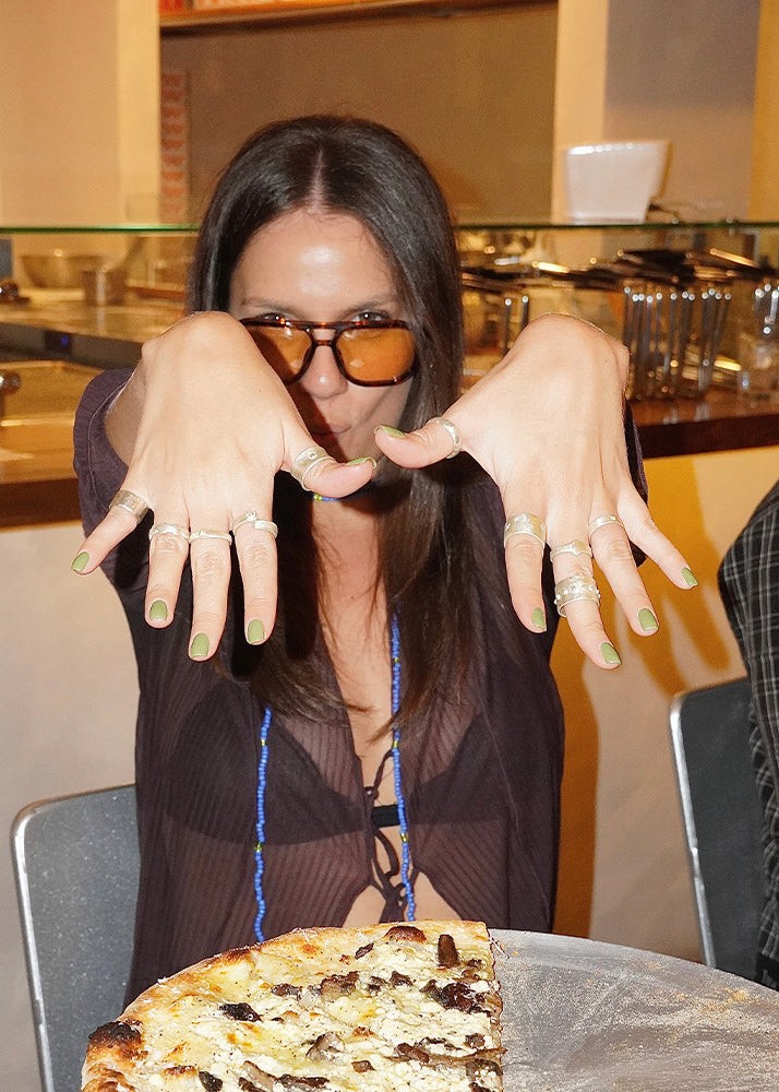 Woman with long nails and multiple rings showing off her silver jewelry in a casual setting.