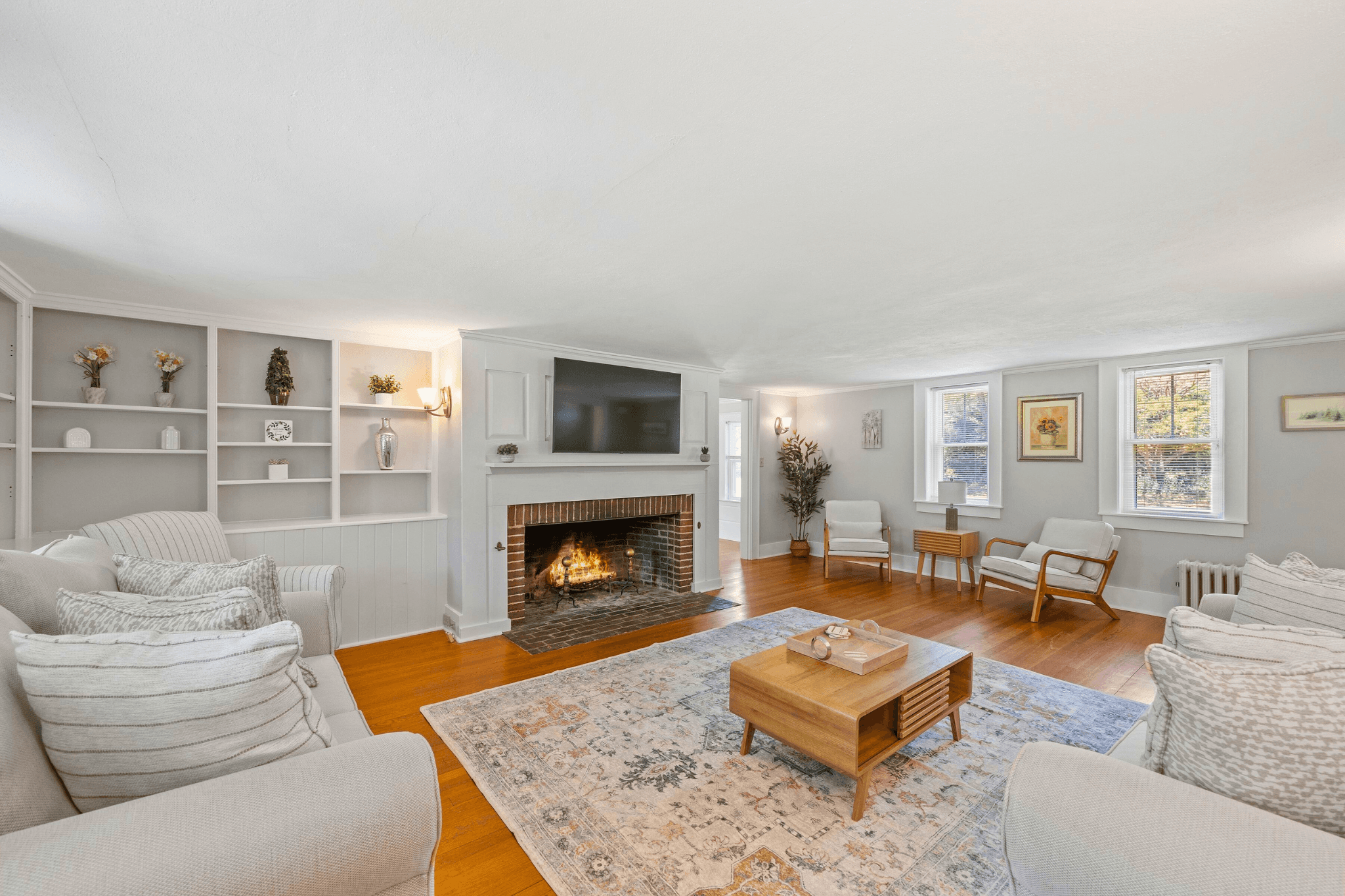 Elegant living room with a white brick fireplace, custom built-ins, hardwood floors, and plush seating, perfect for group Airbnb stays in Concord, New Hampshire.