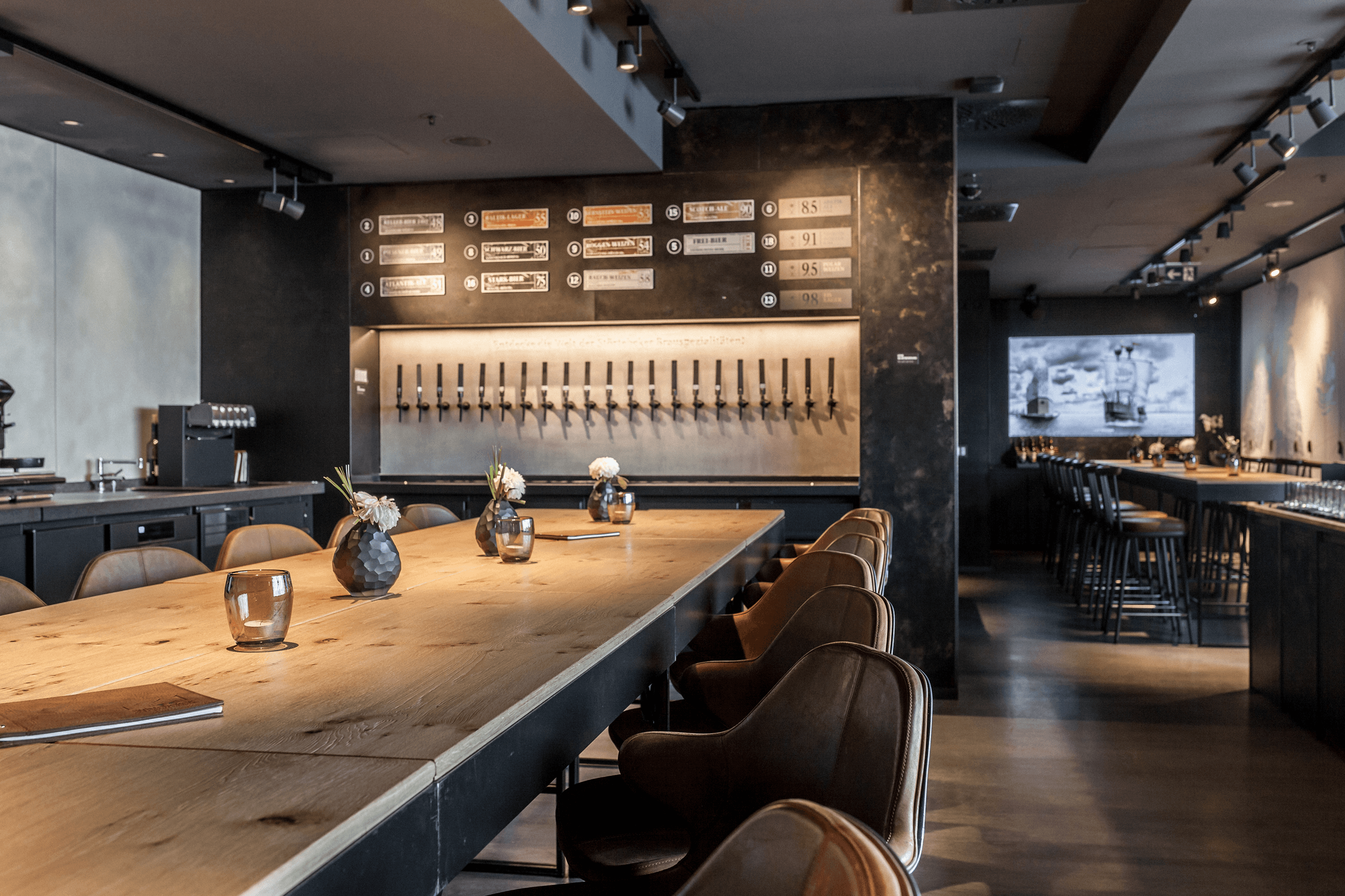 Restaurant with a long wooden table, bar taps, and seating.