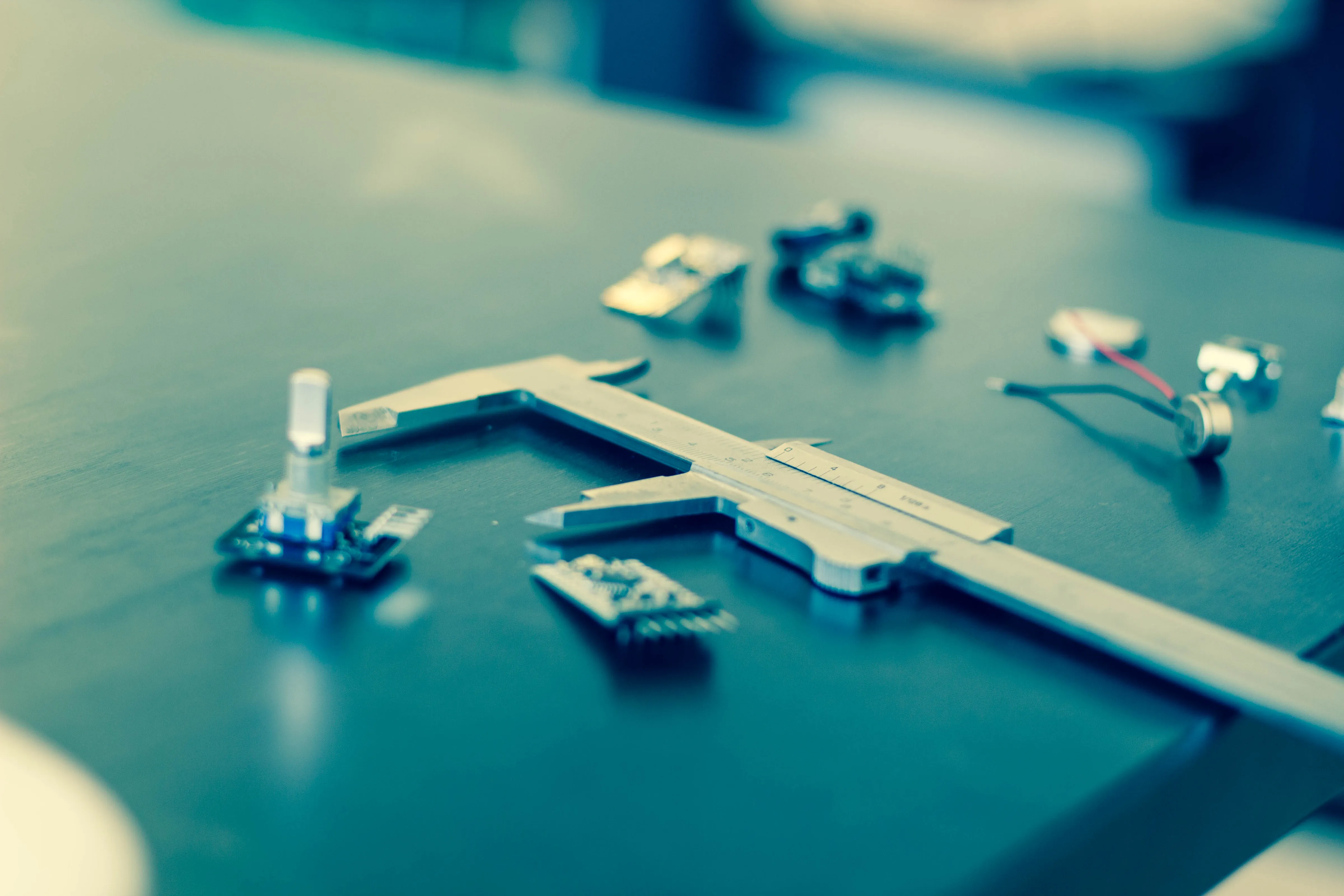 Components on a table with a sliding caliper symbolizing prototyping.