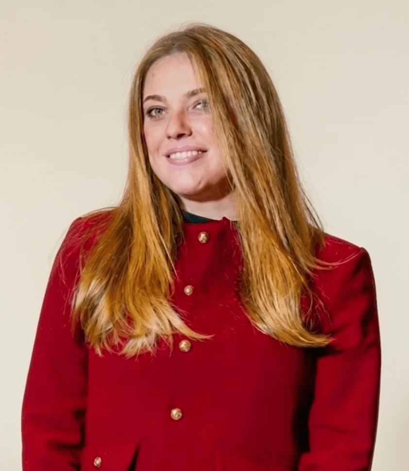 A man with glasses and a brown shirt, crossing his arms.