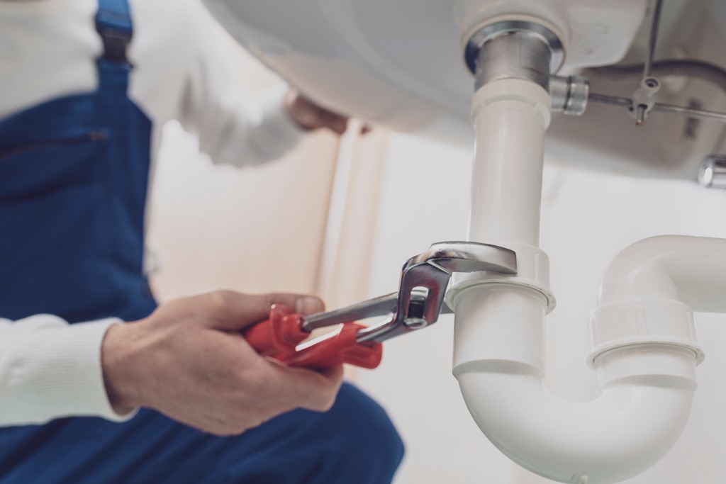 A gas engineer adjusting a boiler and taking notes on a clipboard