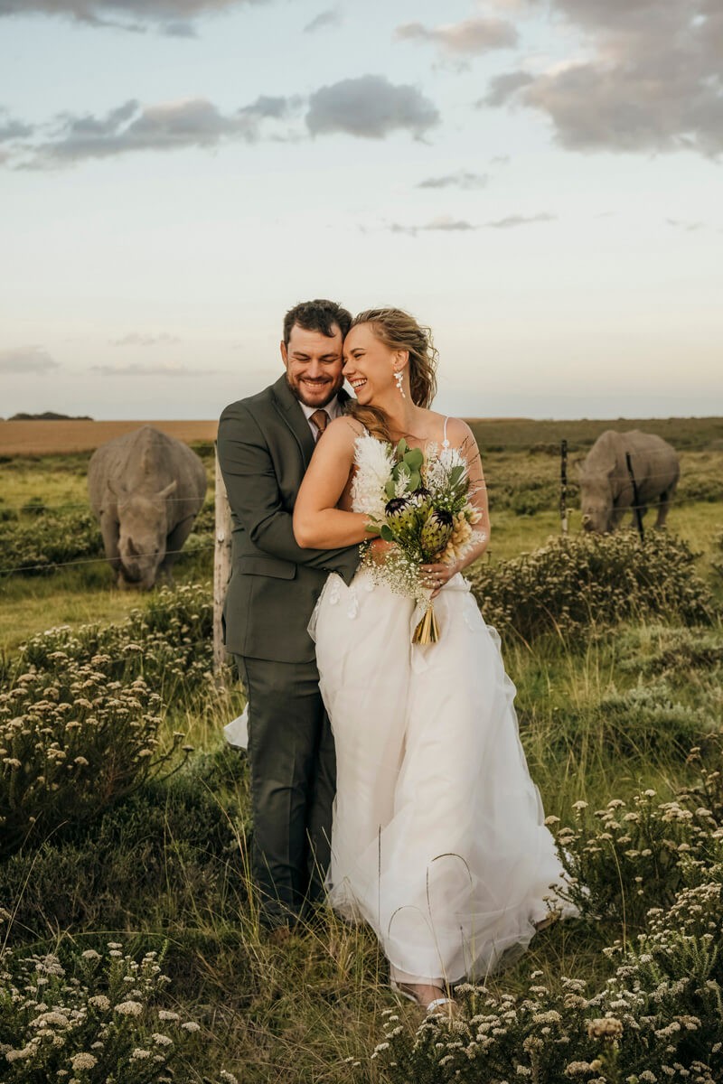 Bride and groom with rhino in background during safari wedding shoot