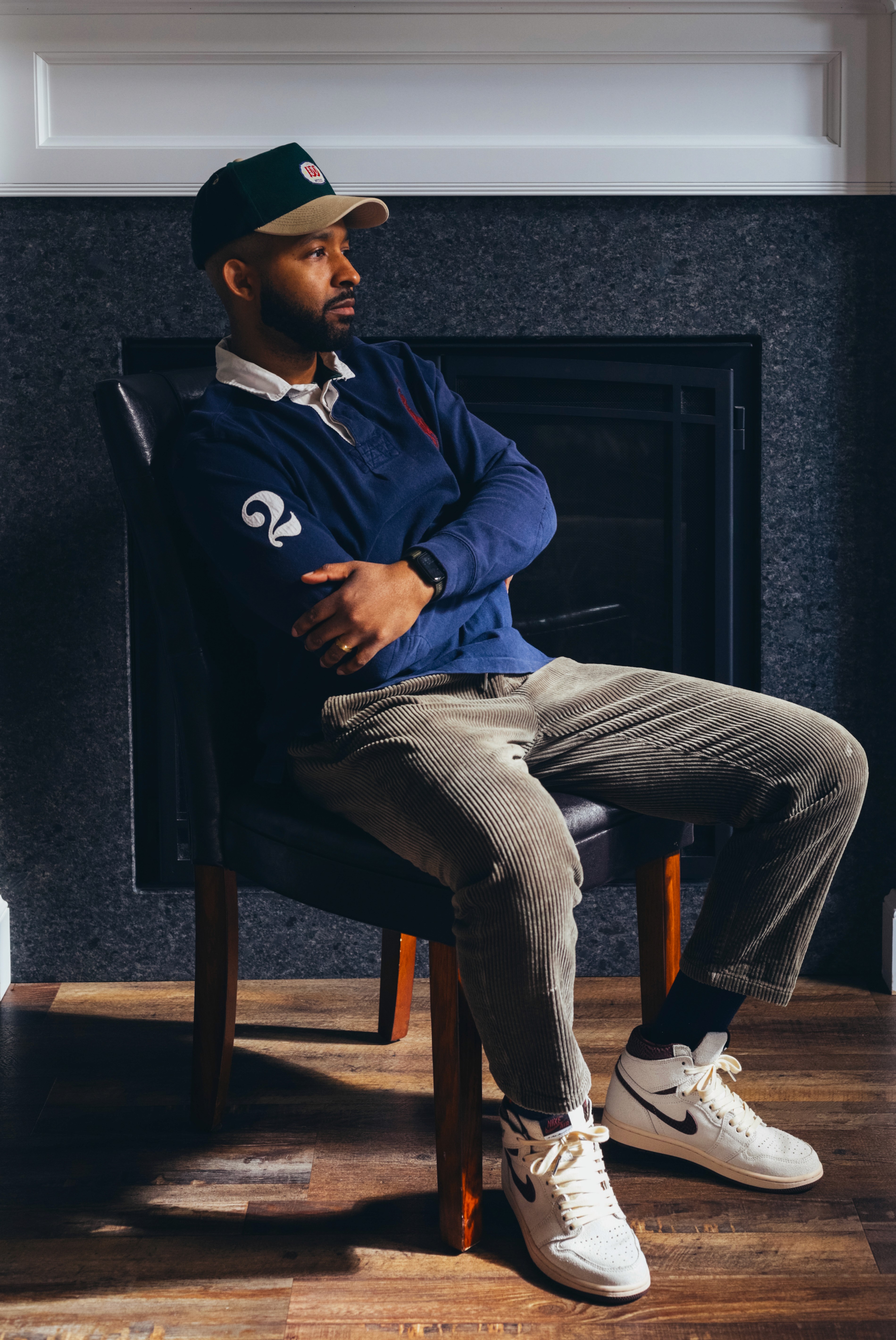 Person wearing a blue puffer jacket and red backpack standing in front of a light blue building on a city street.