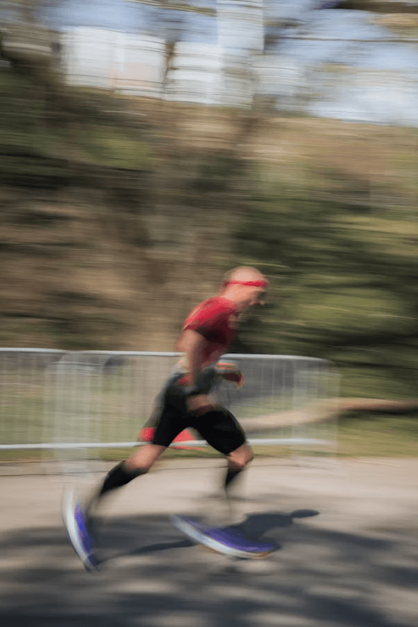 A blurred image of a person in athletic clothing running outdoors, with trees in the background.