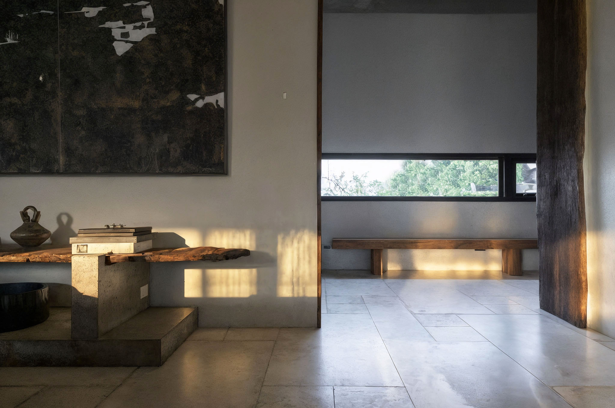 侘寂空間內透光自然照亮木凳與展示平台，抽象畫作與陶器呈現簡約藝術感