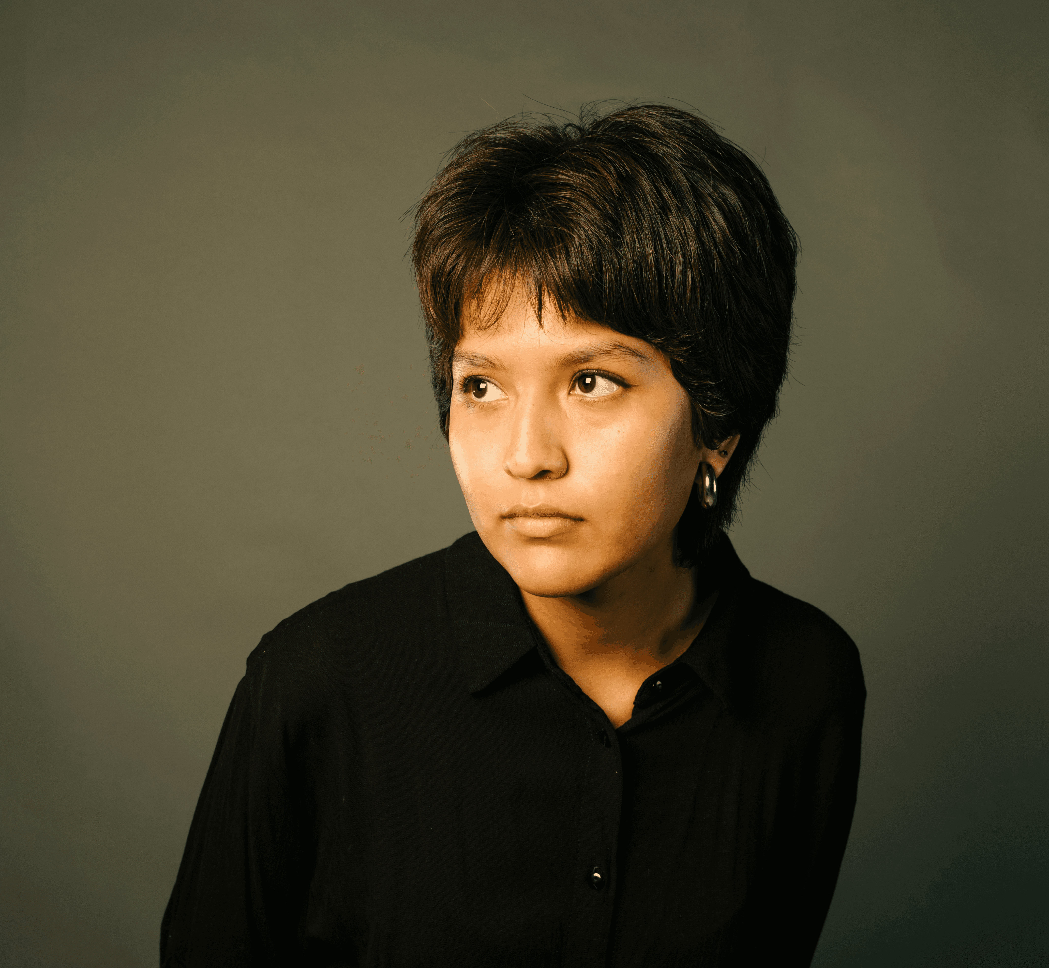 Portrait of a studio team member — person with short dark hair and a hoop earring in a black shirt