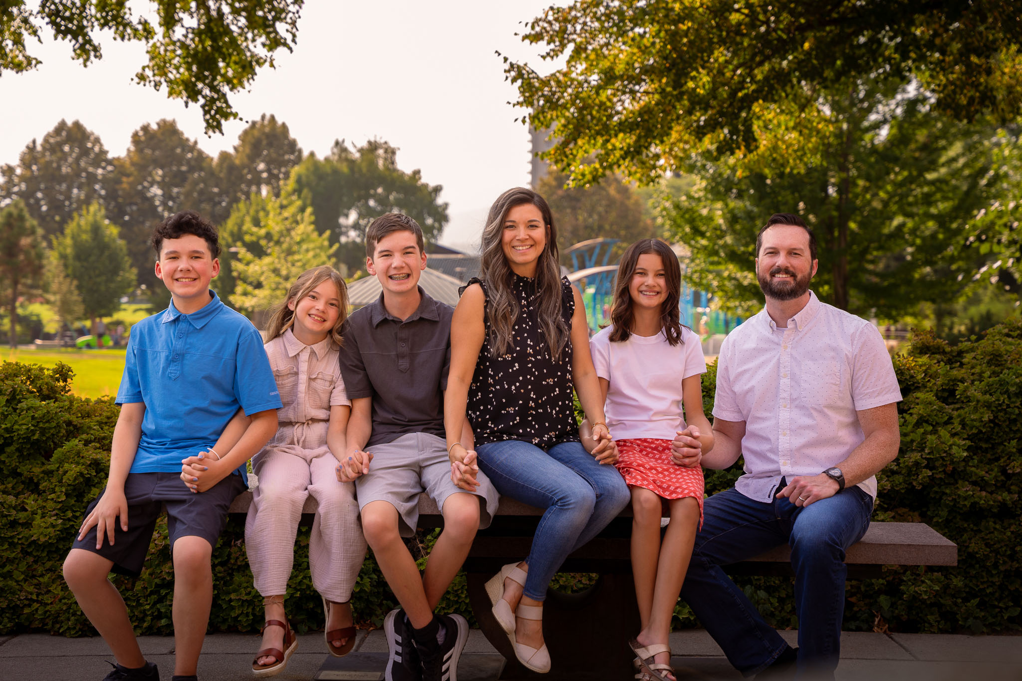 The beautiful family sitting on a bench with trees in the background