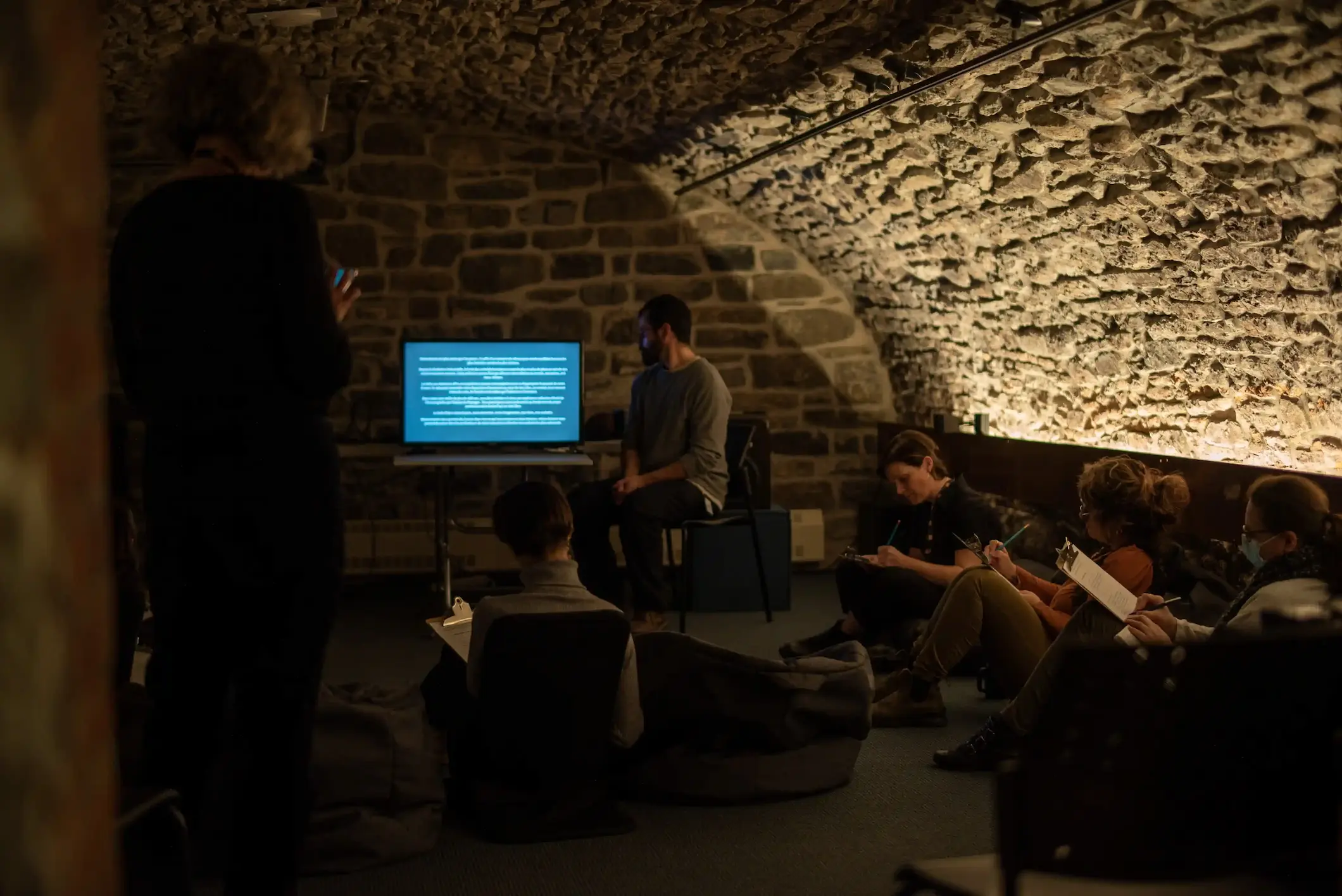 Gros plan sur un mur de pierre voûté équipé de petits haut-parleurs orientés vers une installation immersive.