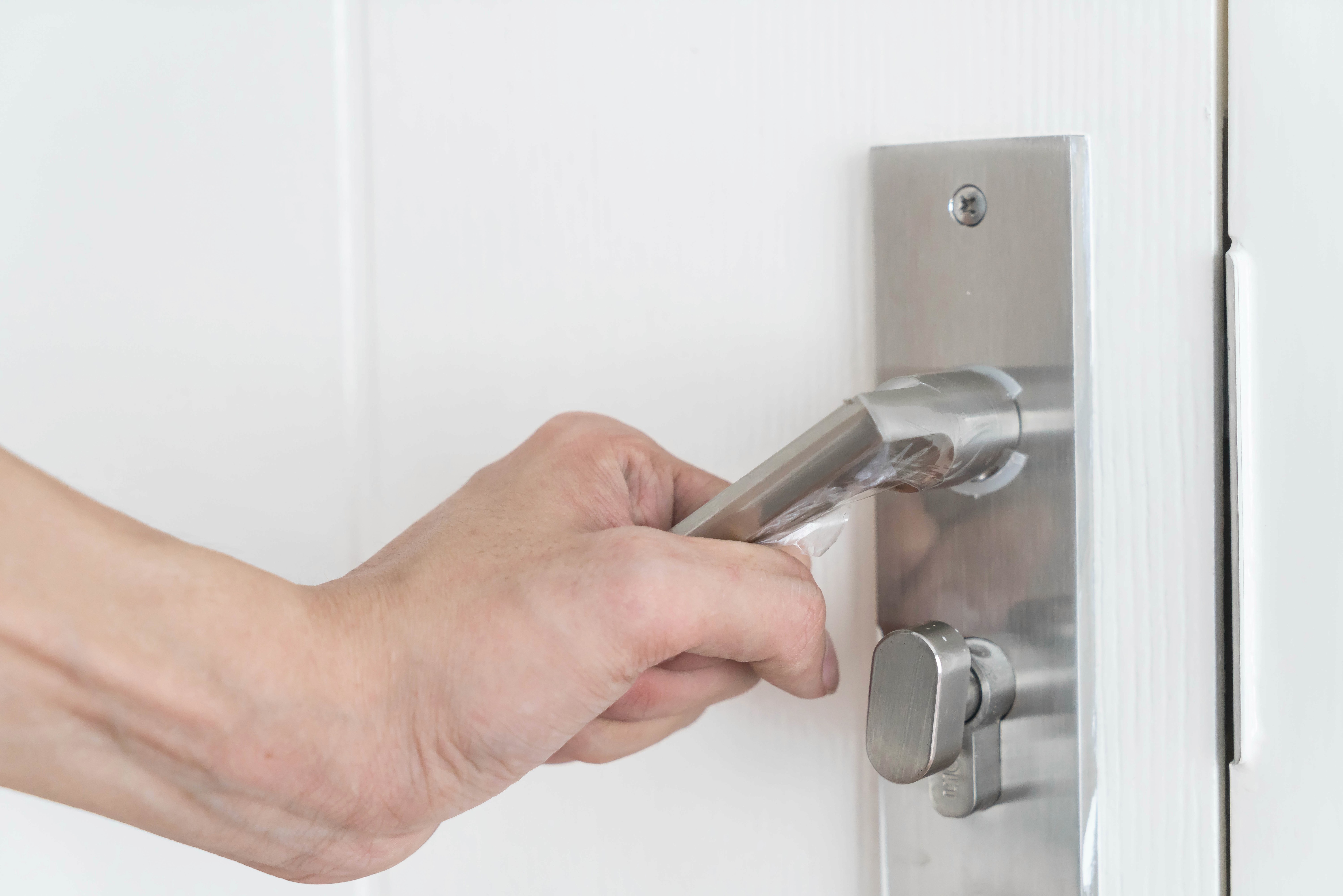 A hand grabbing and pulling down a door handle