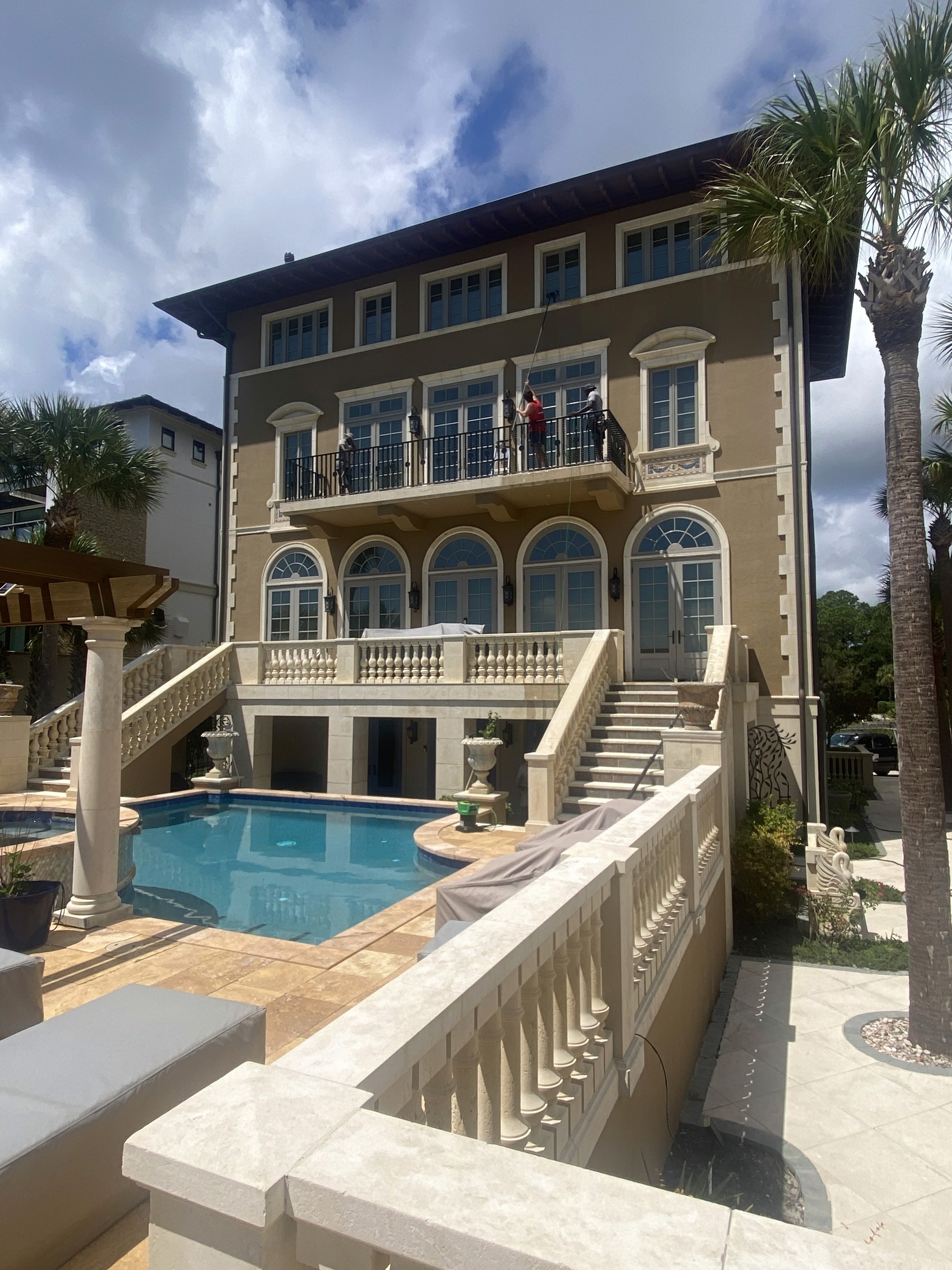 Technician using a squeegee to clean exterior glass windows on a Hilton Head home.