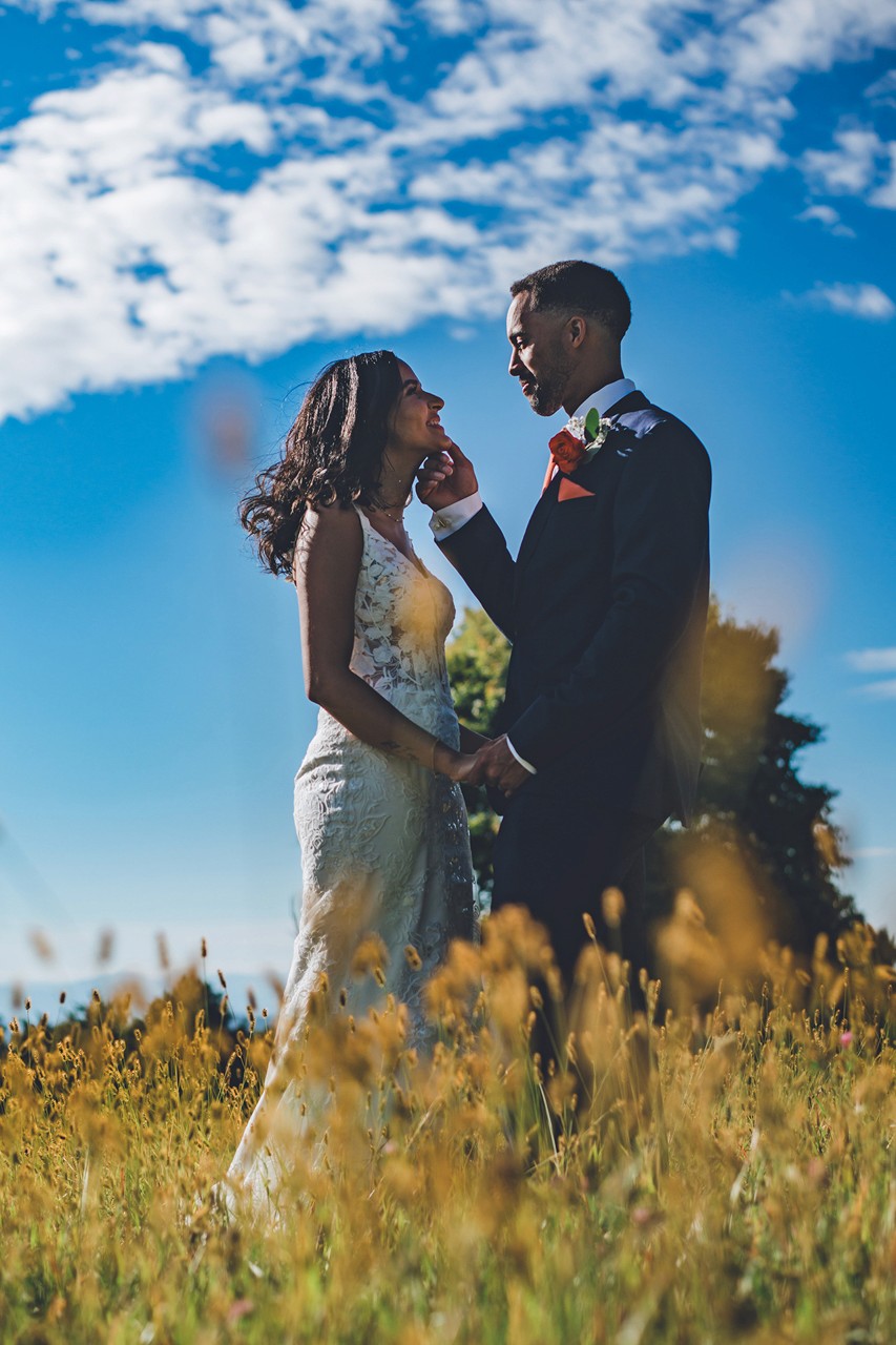 Happy couple on their wedding day in a field, woman in a white dress and man in a suit.
