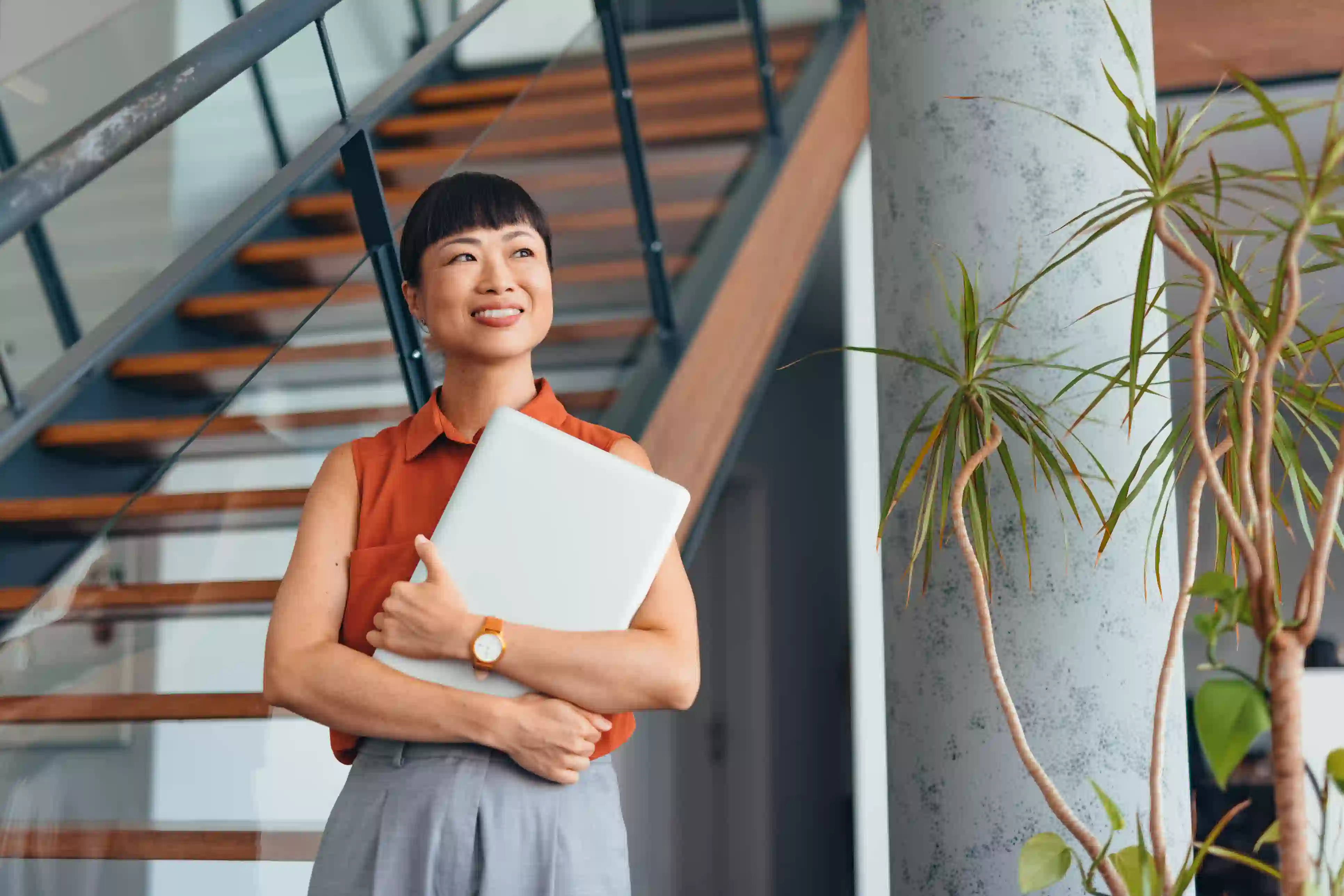 Confident professional standing with documents in hand, signifying ongoing personal and professional growth.