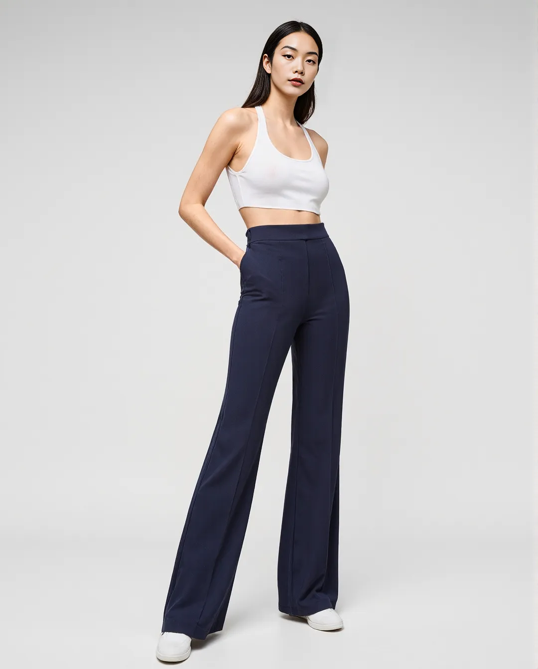 Minimalist fashion photography featuring navy high-waisted trousers paired with white crop top against neutral background