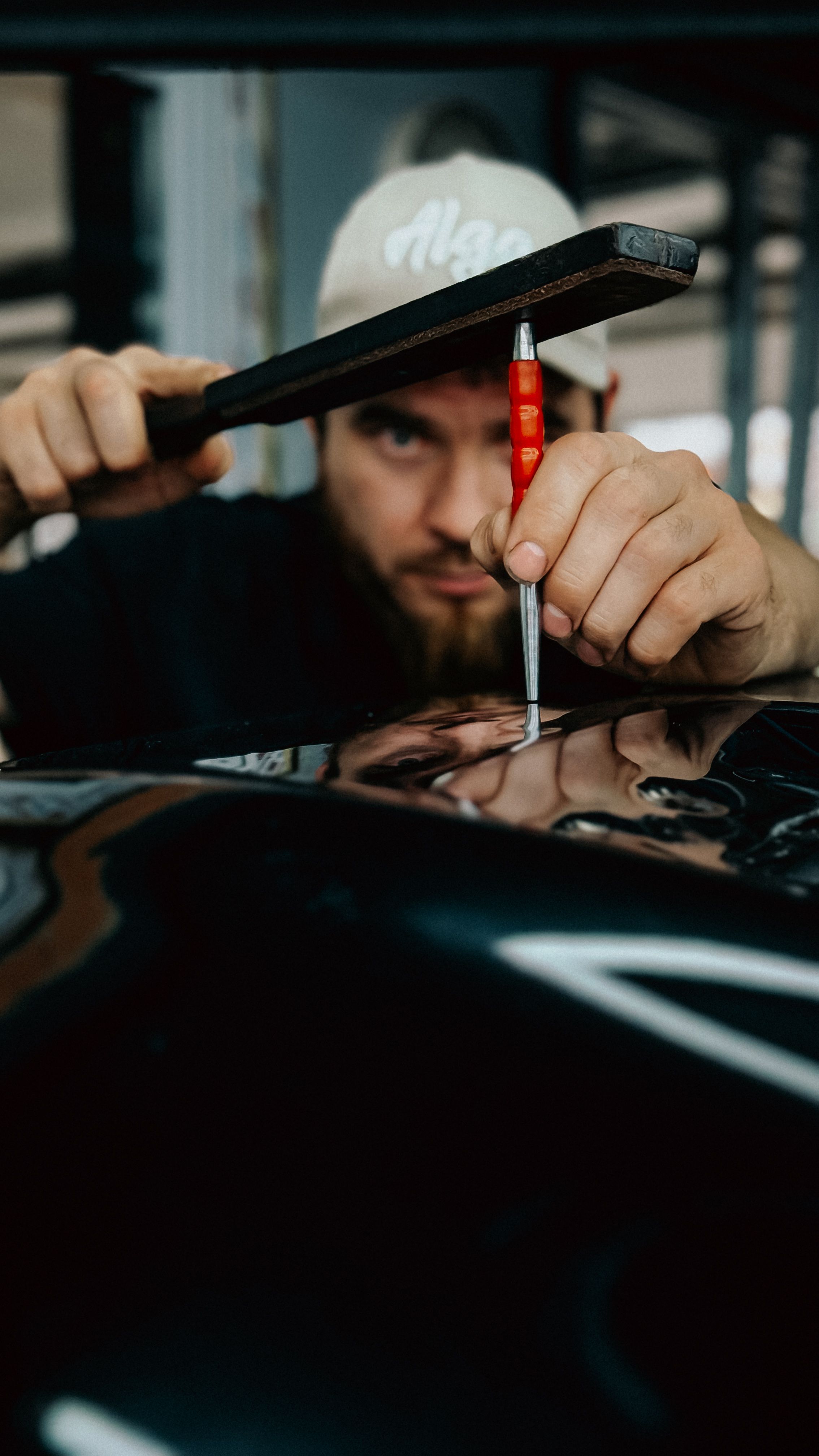 Technicien utilisant un outil de débosselage sur une portière en atelier