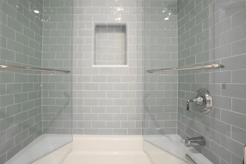 Alcove tub and surrounding blue tiled shower walls with chrome fixtures and shower niche from the Big Canyon Remodel project. Photo by Chris Darnall.