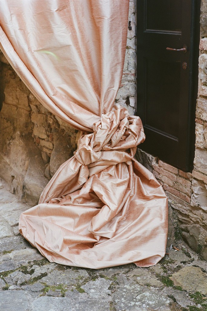 Soft pink fabric draping detail tied against a stone wall at a wedding location