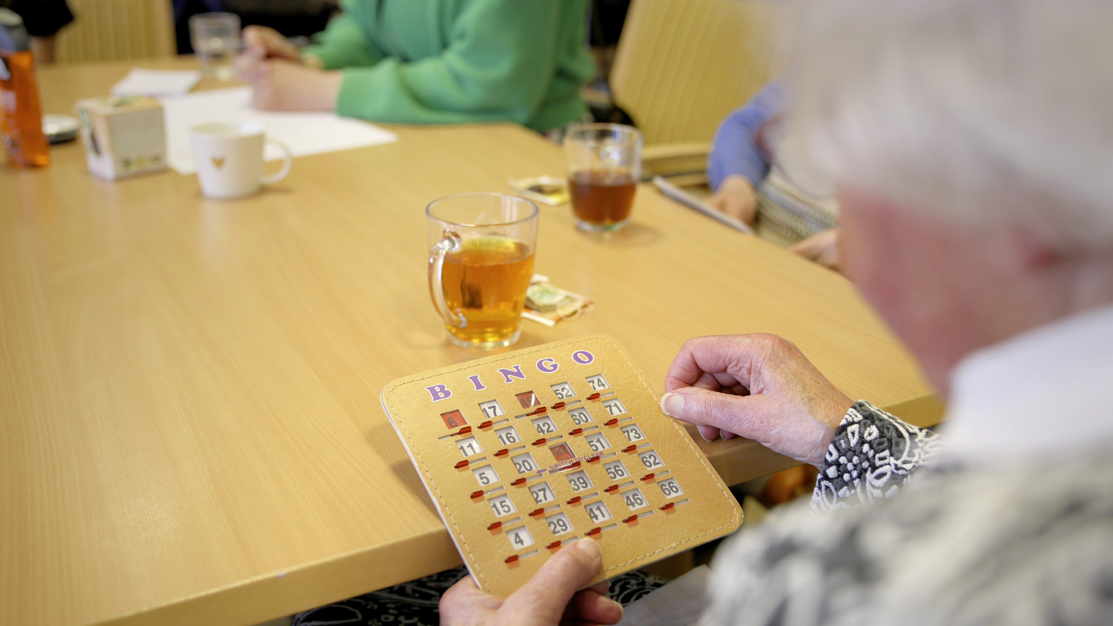 Sfeershot: Kind houdt microfoon met Cedra-logo vast tijdens interview met oudere bewoner in verzorgingstehuis, Dag van de Zorg