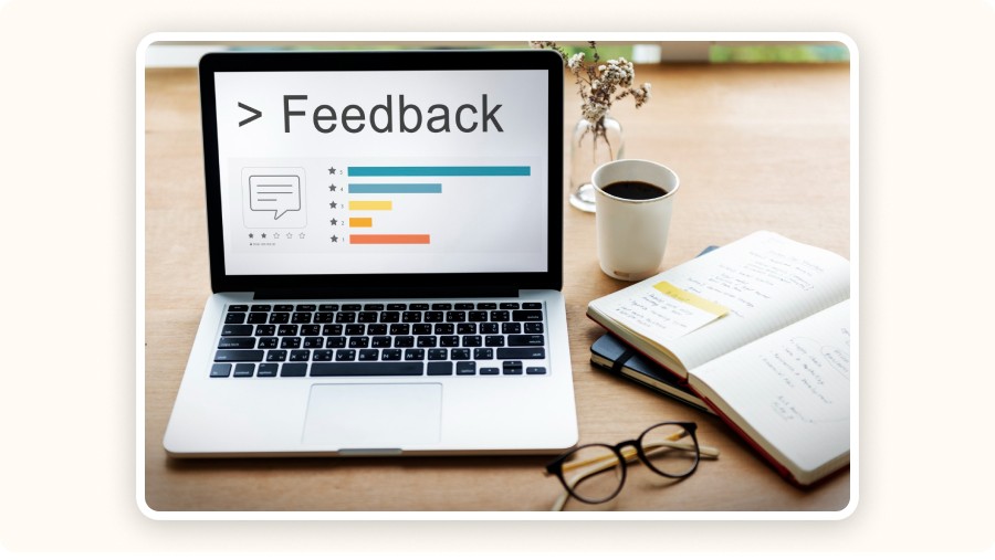 Laptop screen shows feedback survey beside notebook, coffee, and glasses.
