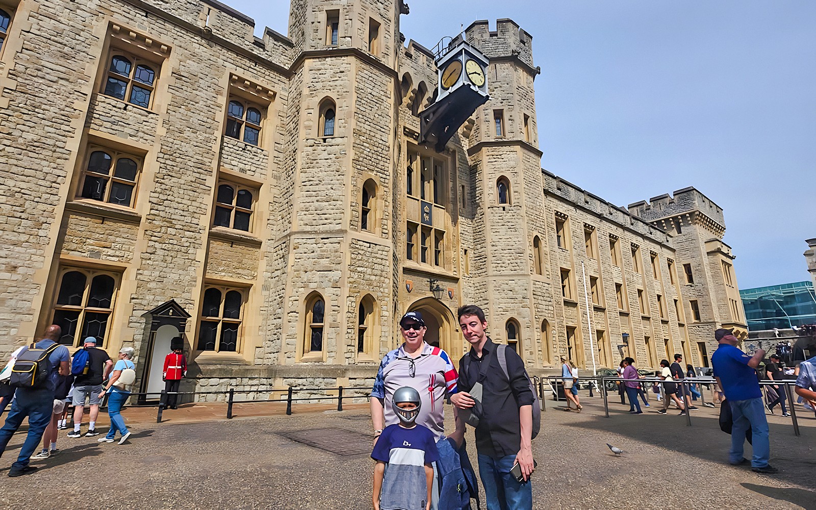 在伦敦塔历史遗址外，游客们在背景中有一位约曼守护者。