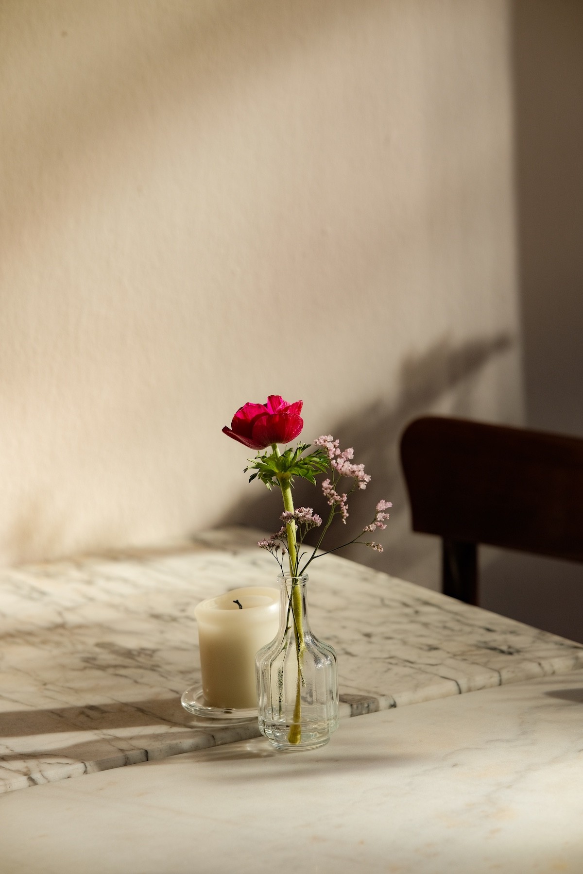 Rote Blume in kleiner Glasvase auf einem Marmortisch im Innenraum der Vermutbar A VER in Köln.