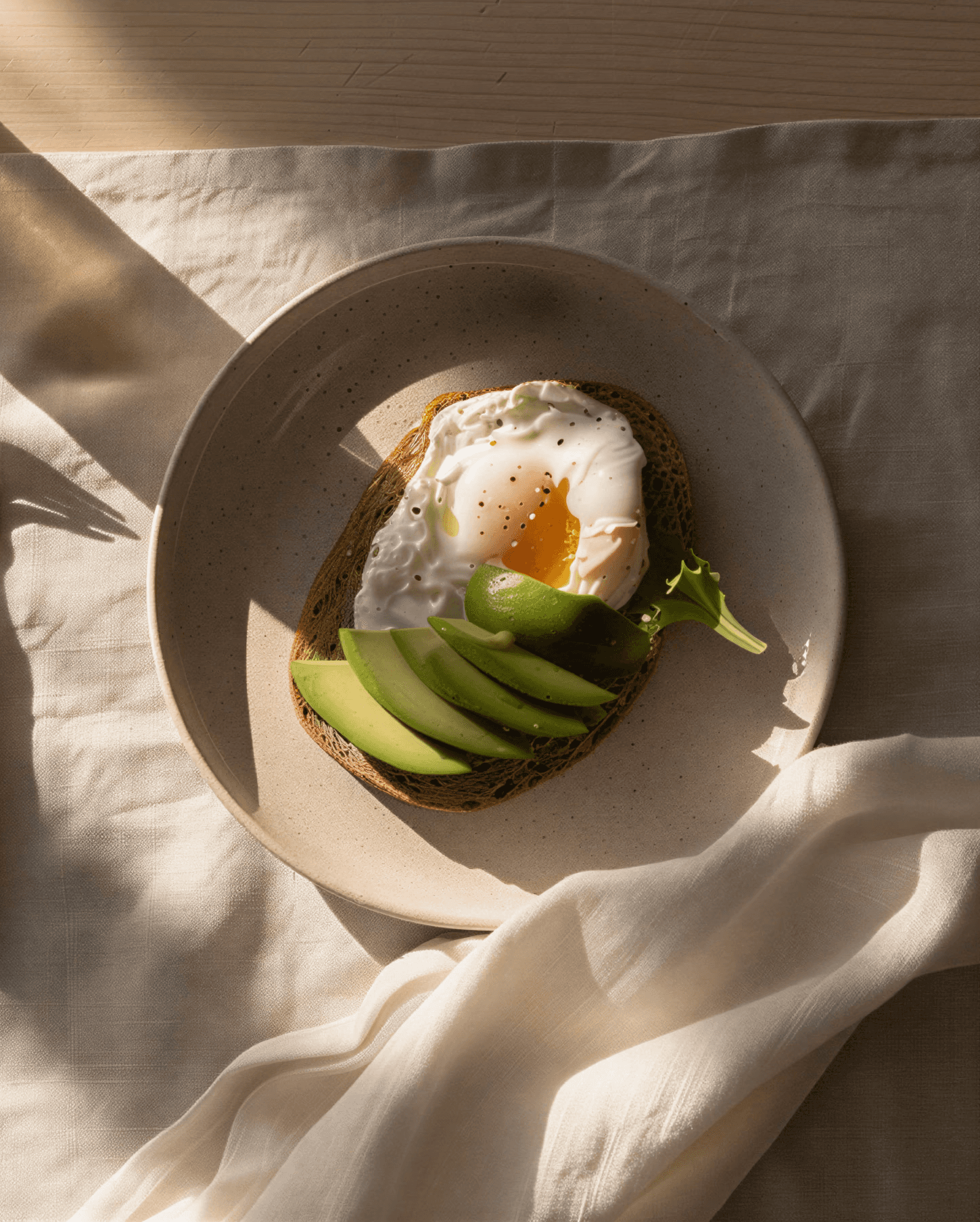 Poached egg and avocado bowl with fresh greens on a white plate
