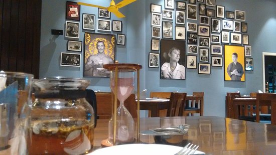 A wall at the Infinitea tea room in Bengaluru adorned with numerous photpgraphs mostly black and white and a few yellow