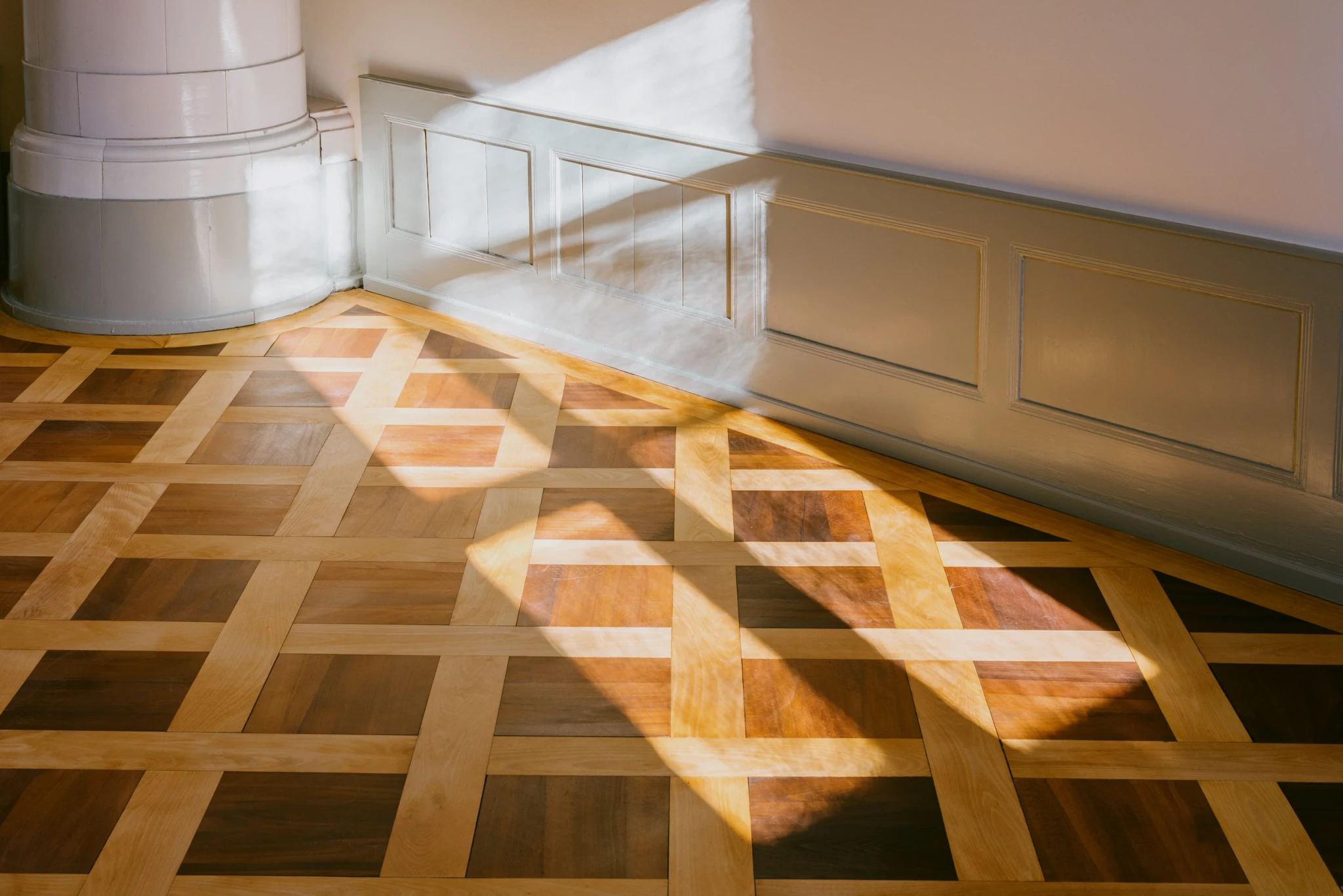 Détail du parquet et du poêle Empire au domaine de Grènetel à La Neuveville, avec boiseries du début du XIXᵉ siècle dans un intérieur historique.