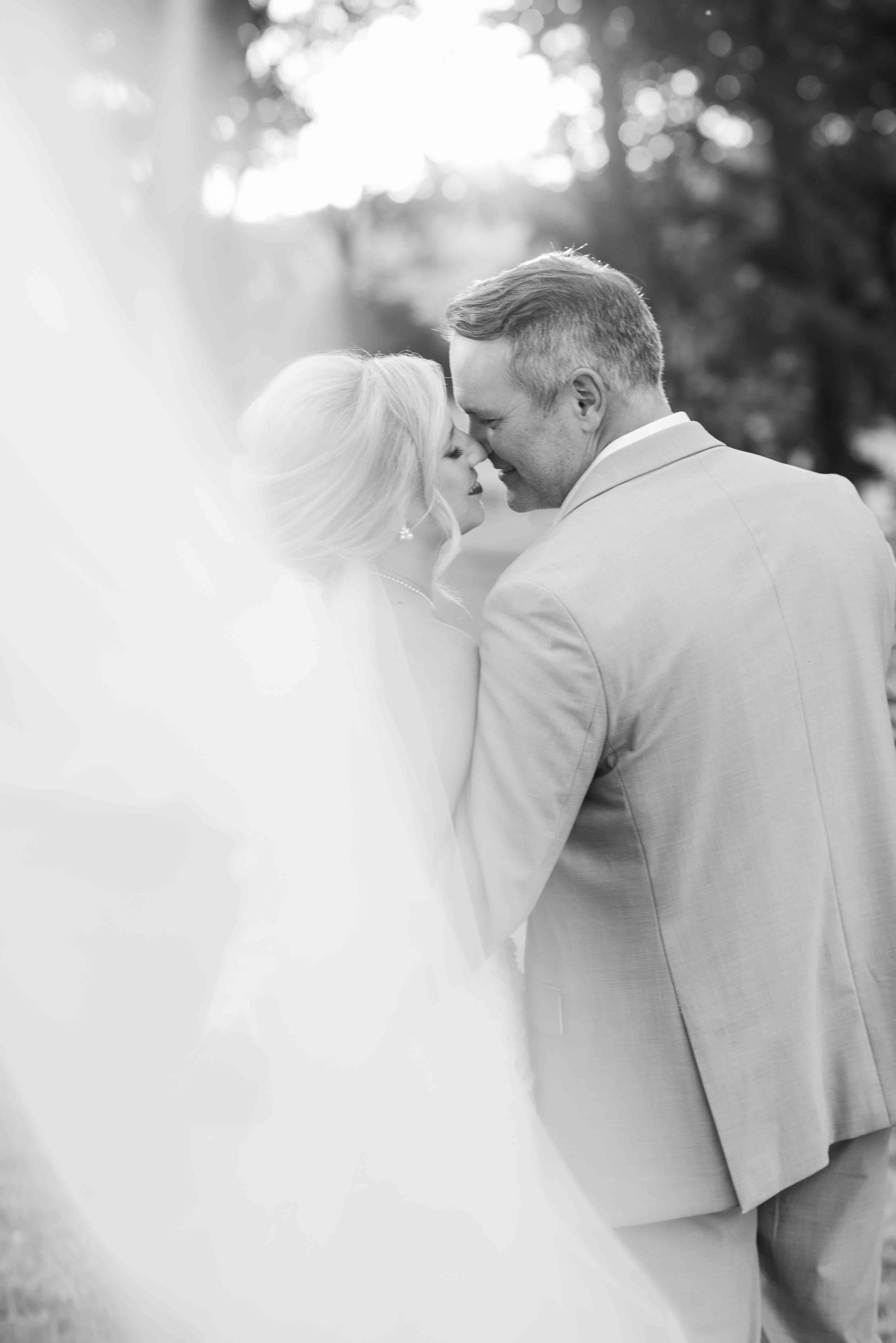 Black and white bride and groom wedding portrait of veil shot with couple kissing.
