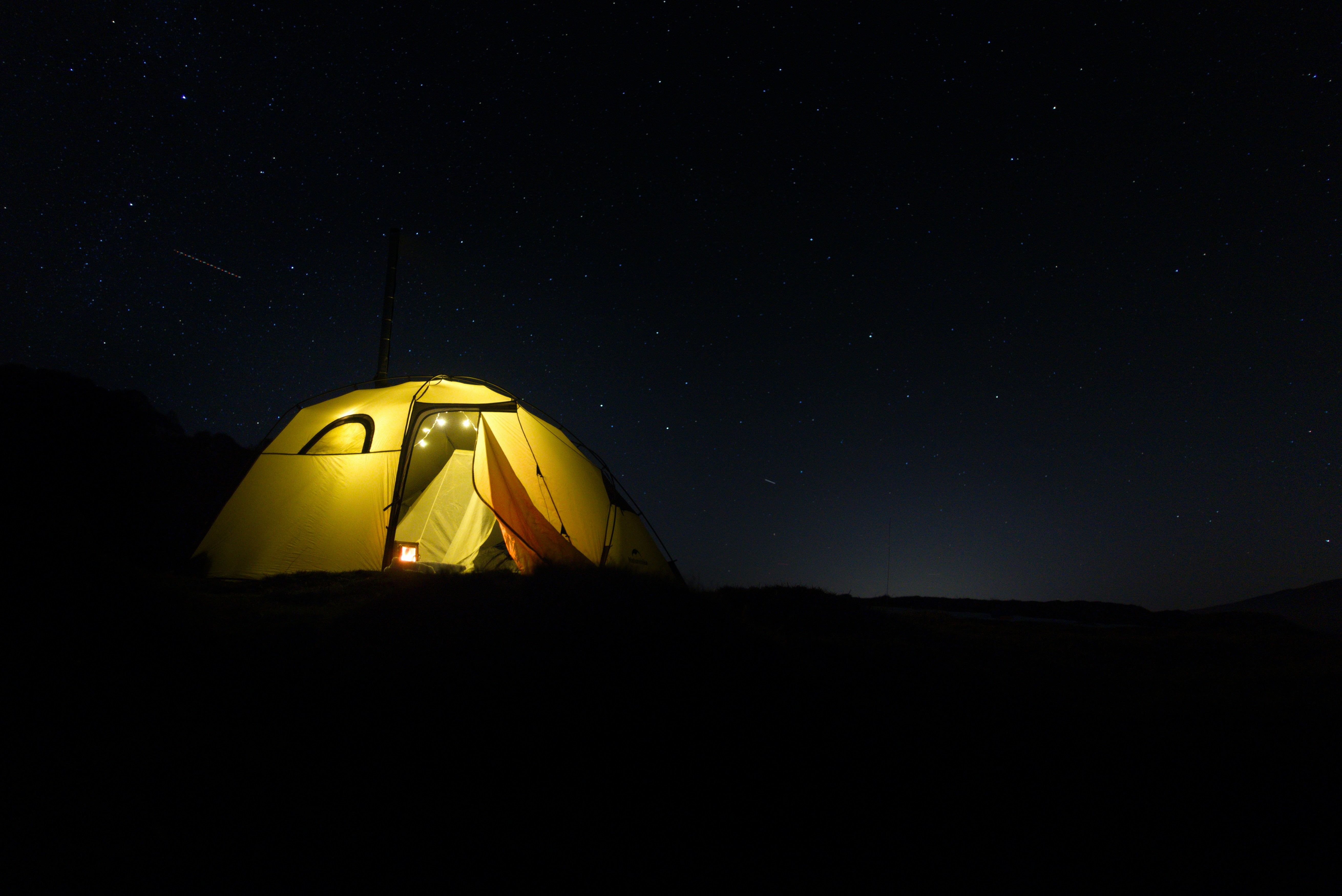 A glowing tent under a starry night sky