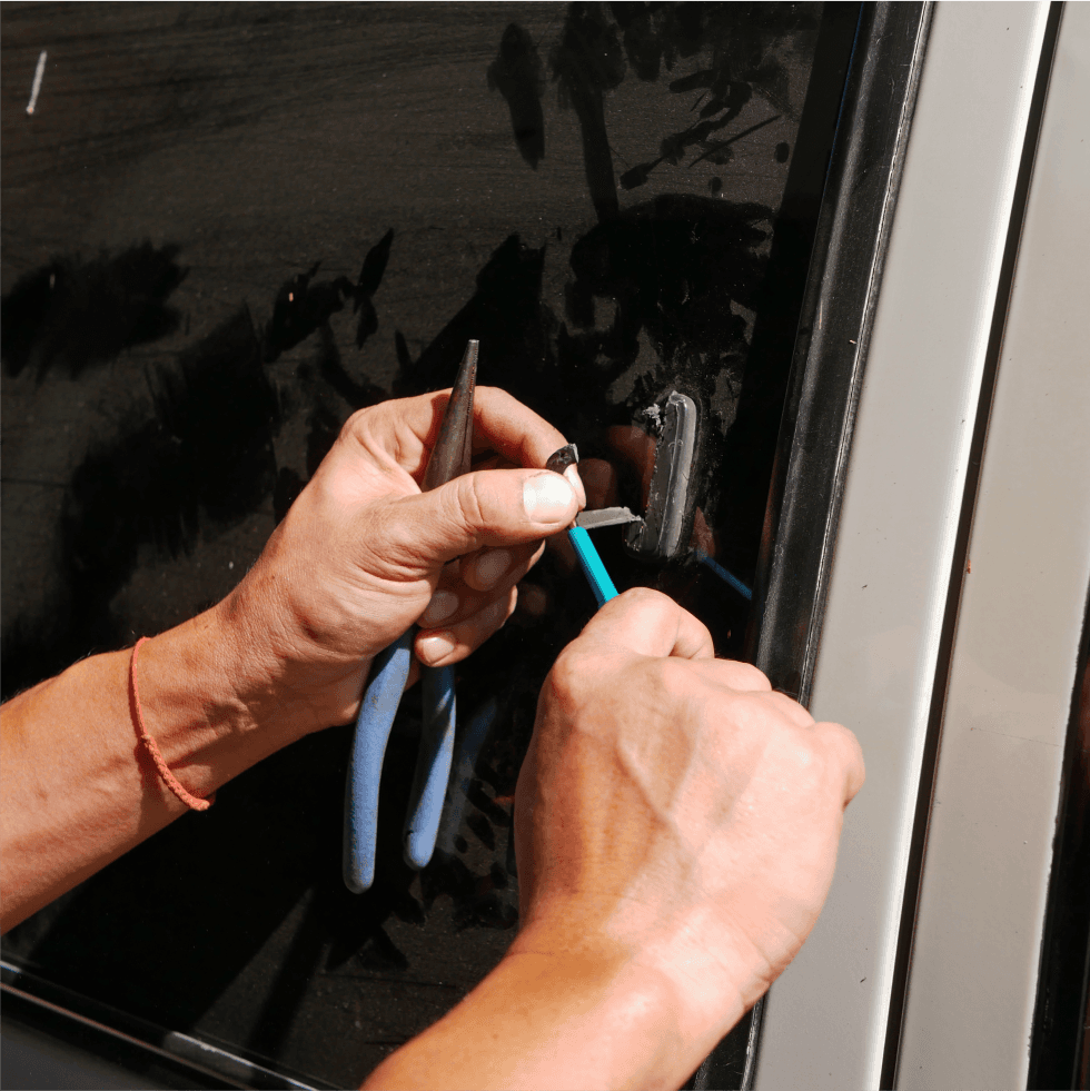 Close-up of hands using pliers to adjust a lock on a door.