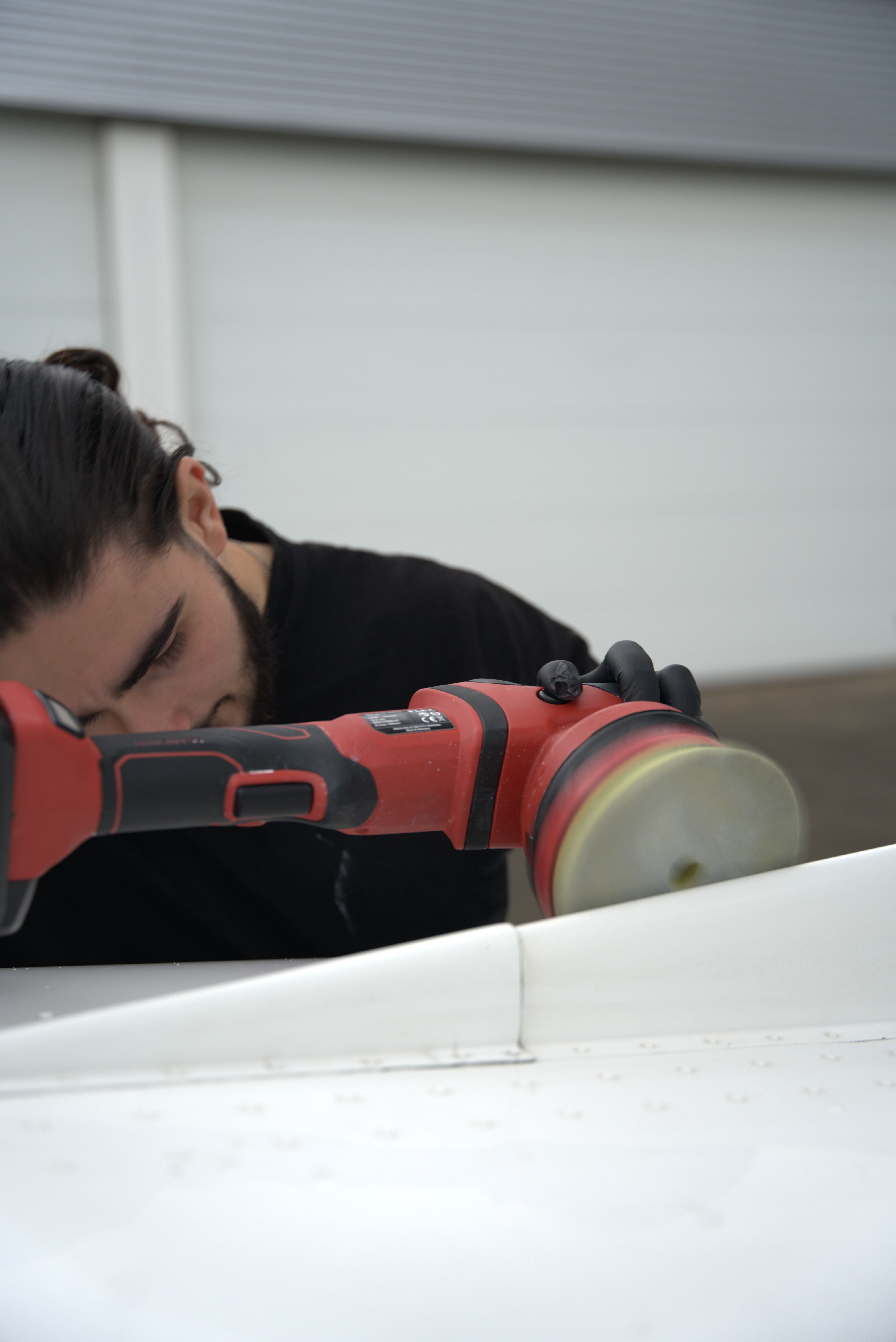 Professionele vliegtuigdetailing: close-up van het polijsten van een vliegtuigvleugel met een polijstmachine.