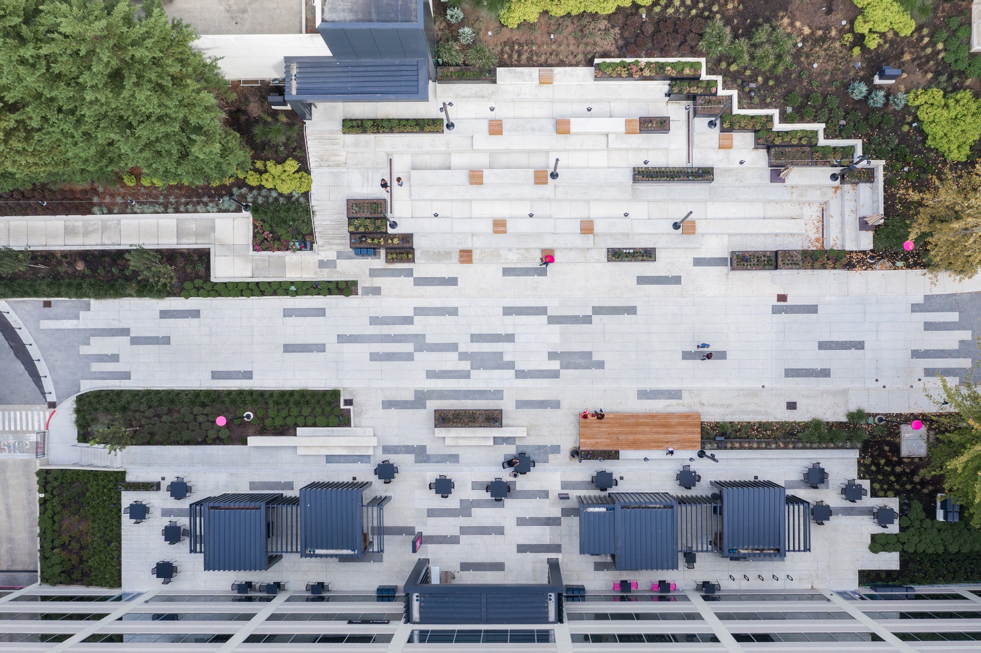 Aerial view of T-Mobile's central plaza, featuring a striking mosaic of grey and white rectangular pavers, outdoor pavilions, and wooden benches scattered across an outdoor amphitheater.