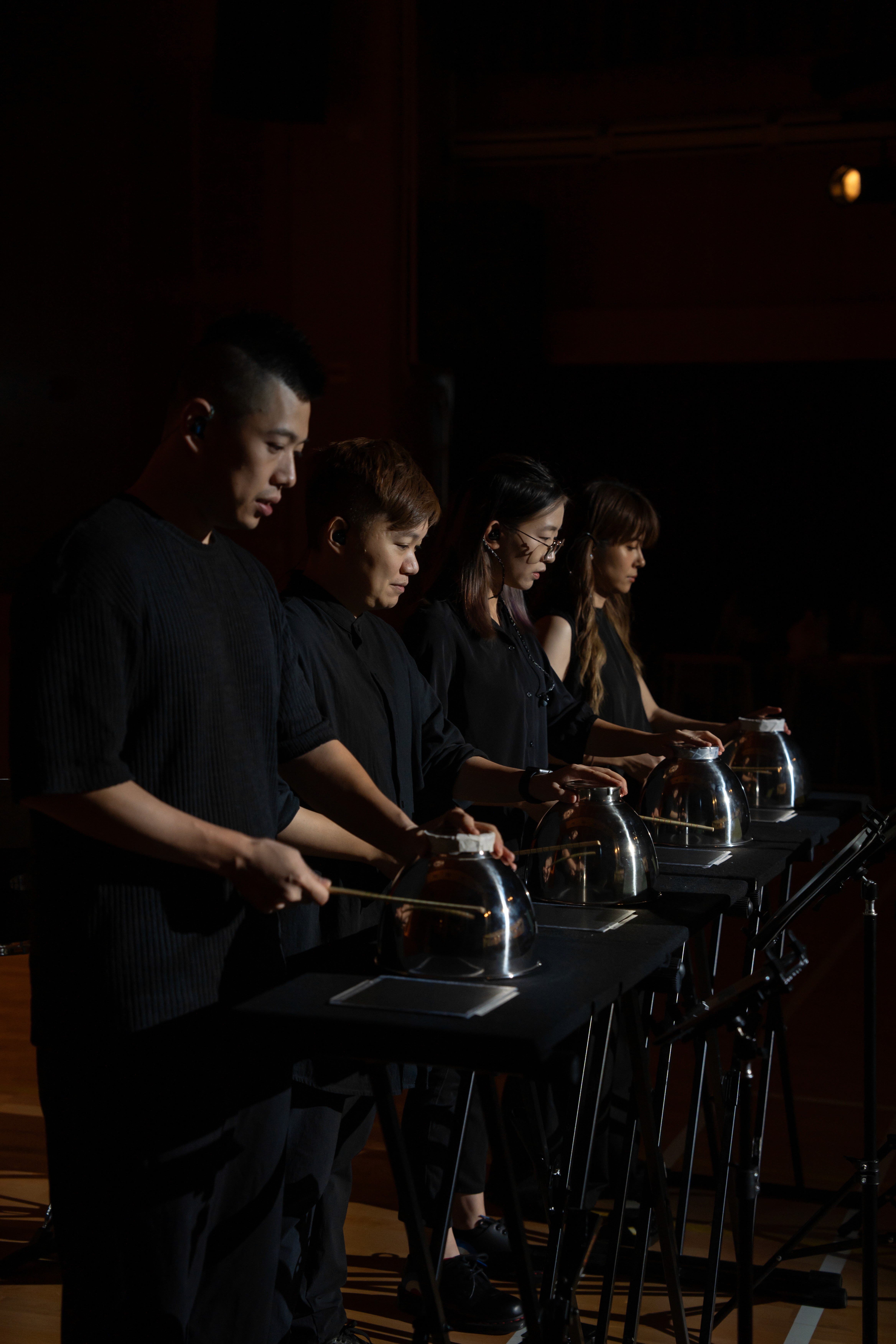 percussion experts are playing their scores in the dark with sticks and bowls