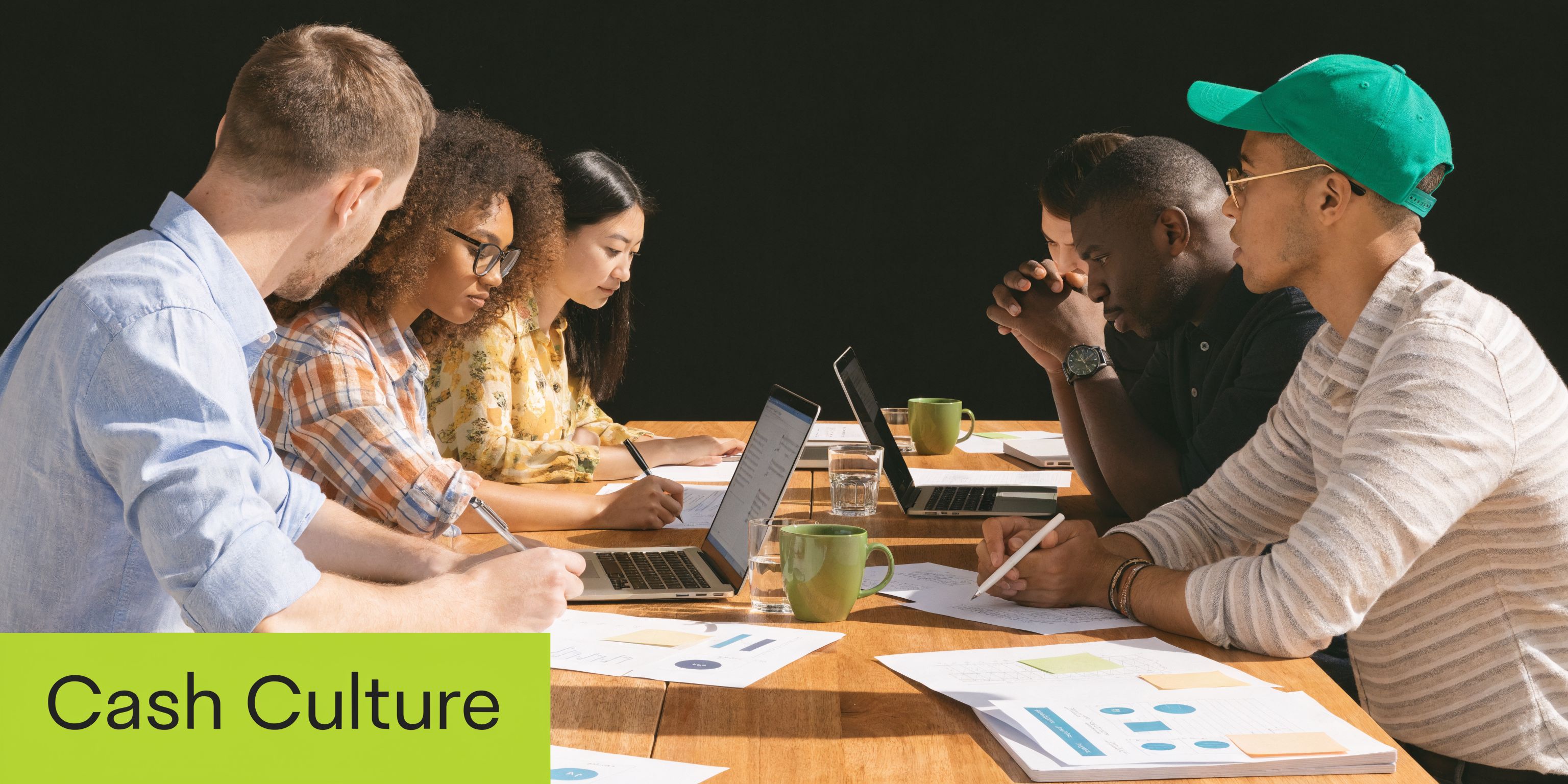 A diverse group of professionals collaborating together on business documents and laptops during a team meeting.