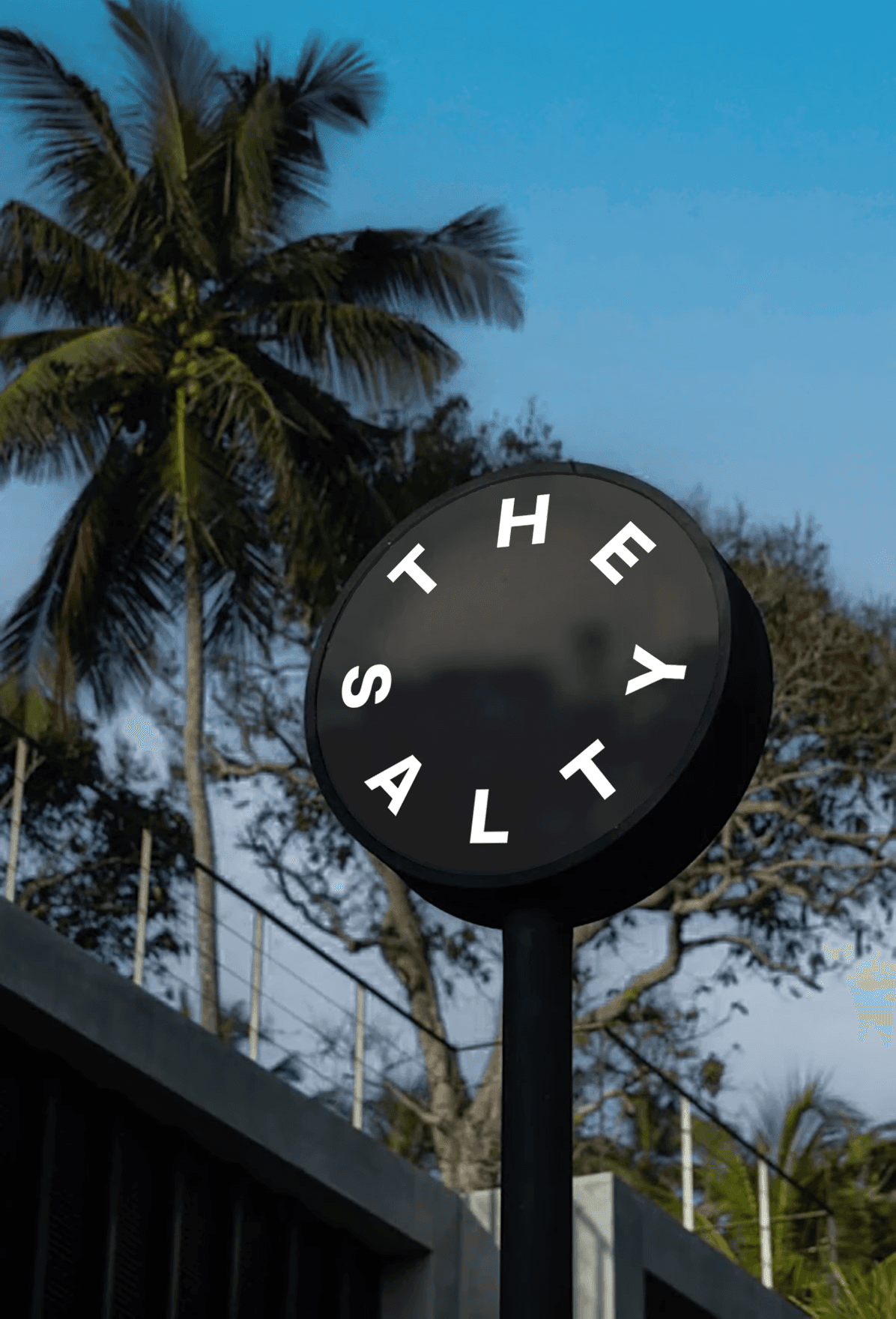 Black rounded outdoor sign displaying The Salty logo mounted outside the property entrance.